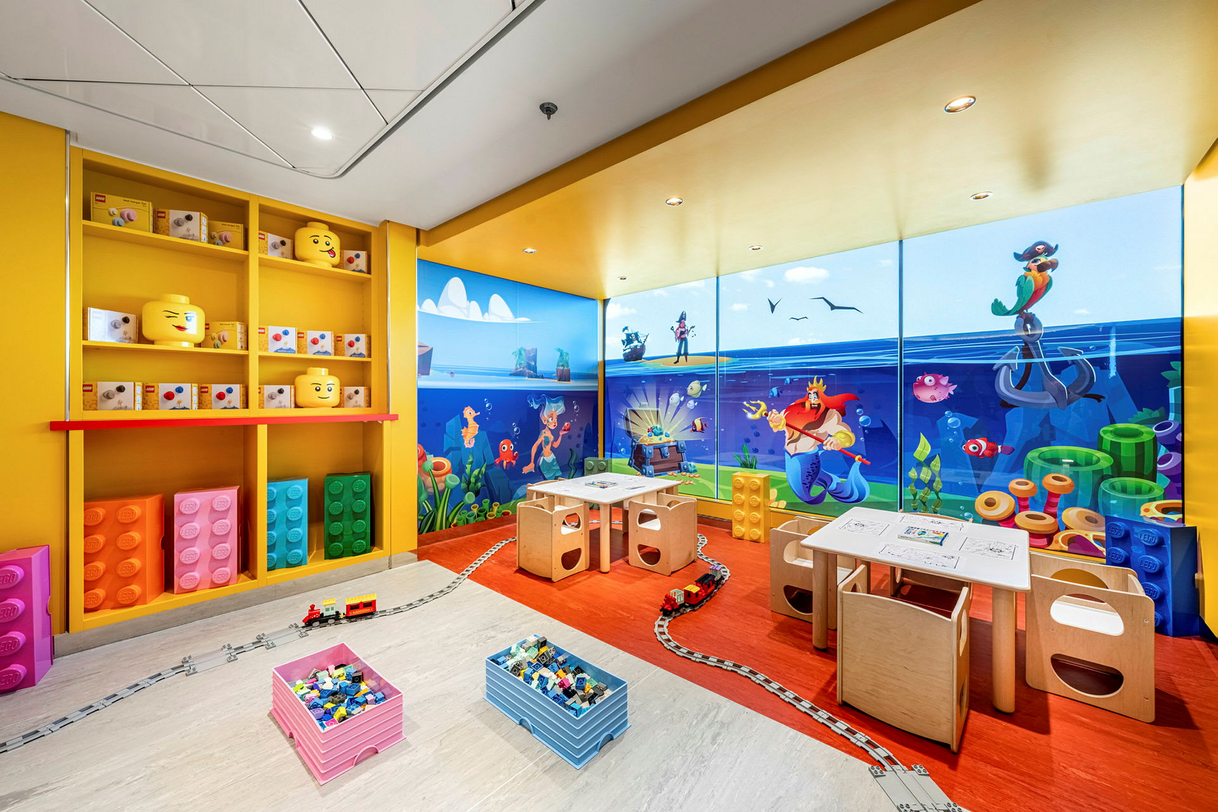 Ett lekutrymme med Lego-tema, färgglada byggklossar och en illustrerad vägg med undervattensmotiv. (AI-genererad text)