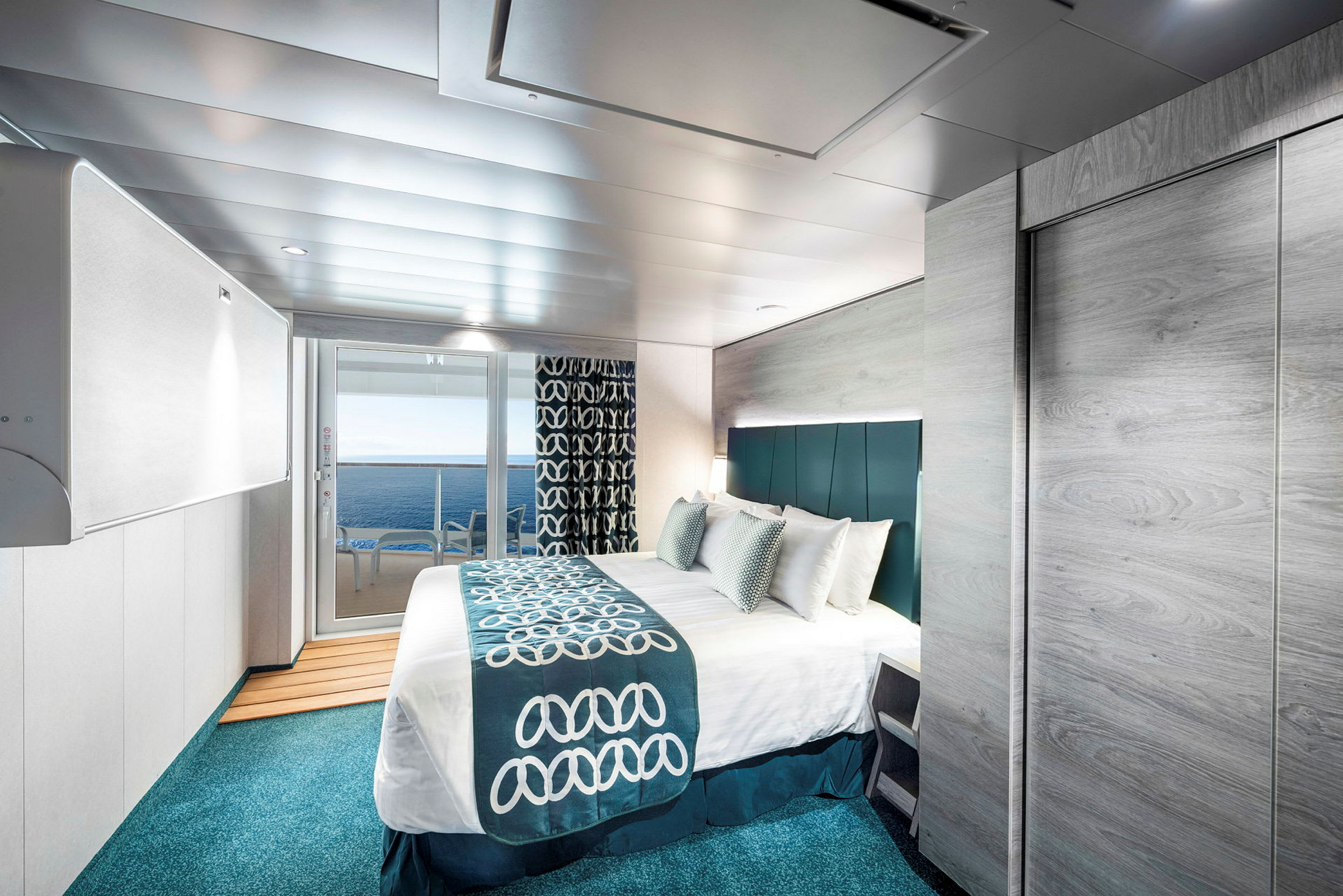 Ett modernt inrett hotellrum med en stor säng, utsikt mot havet genom glasade dörrar, och smakfulla blå och vita detaljer i inredningen. (AI-genererad text)