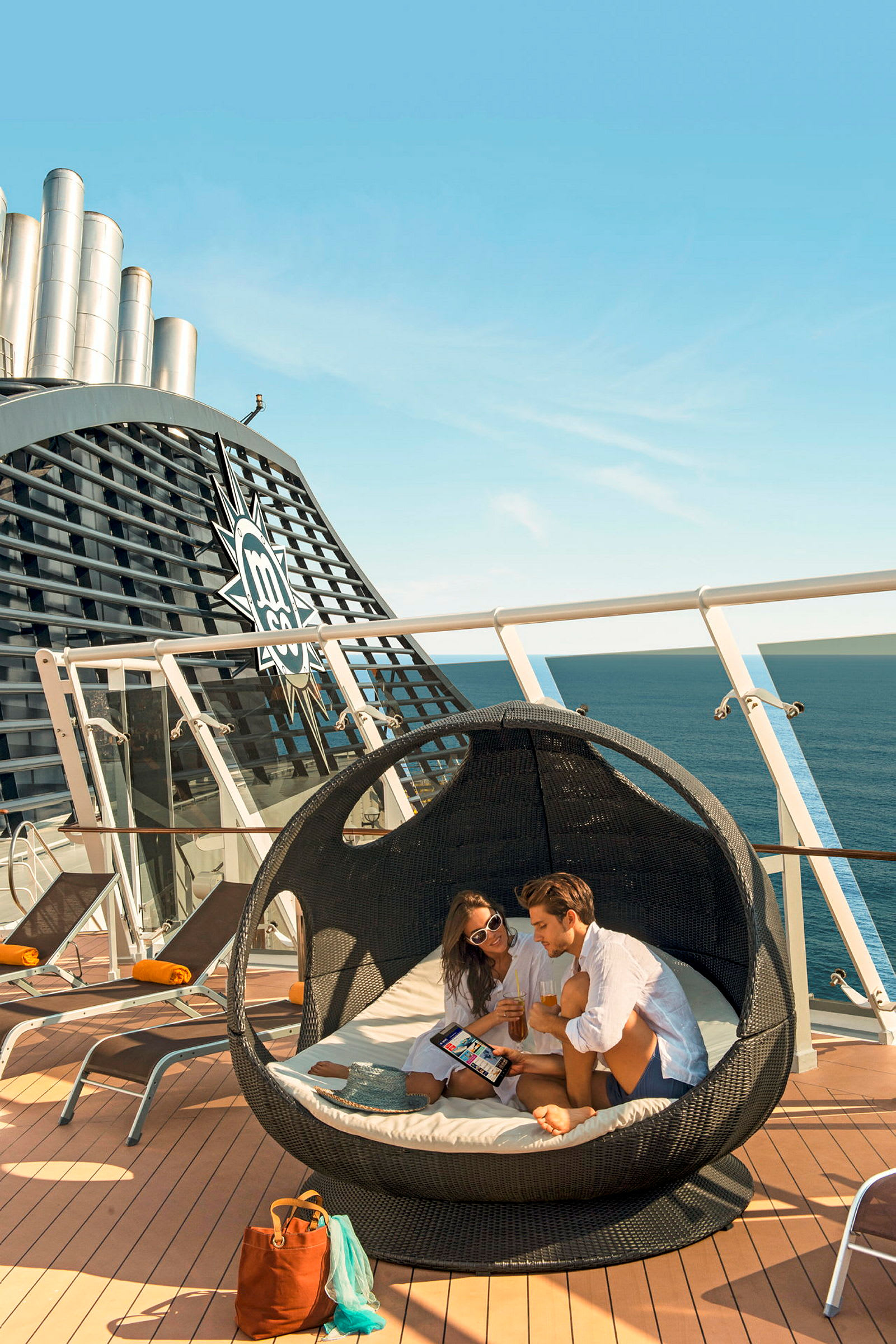 Personer sitter i en rund lounger med havet i bakgrunden på ett kryssningsfartyg. (AI-genererad text)