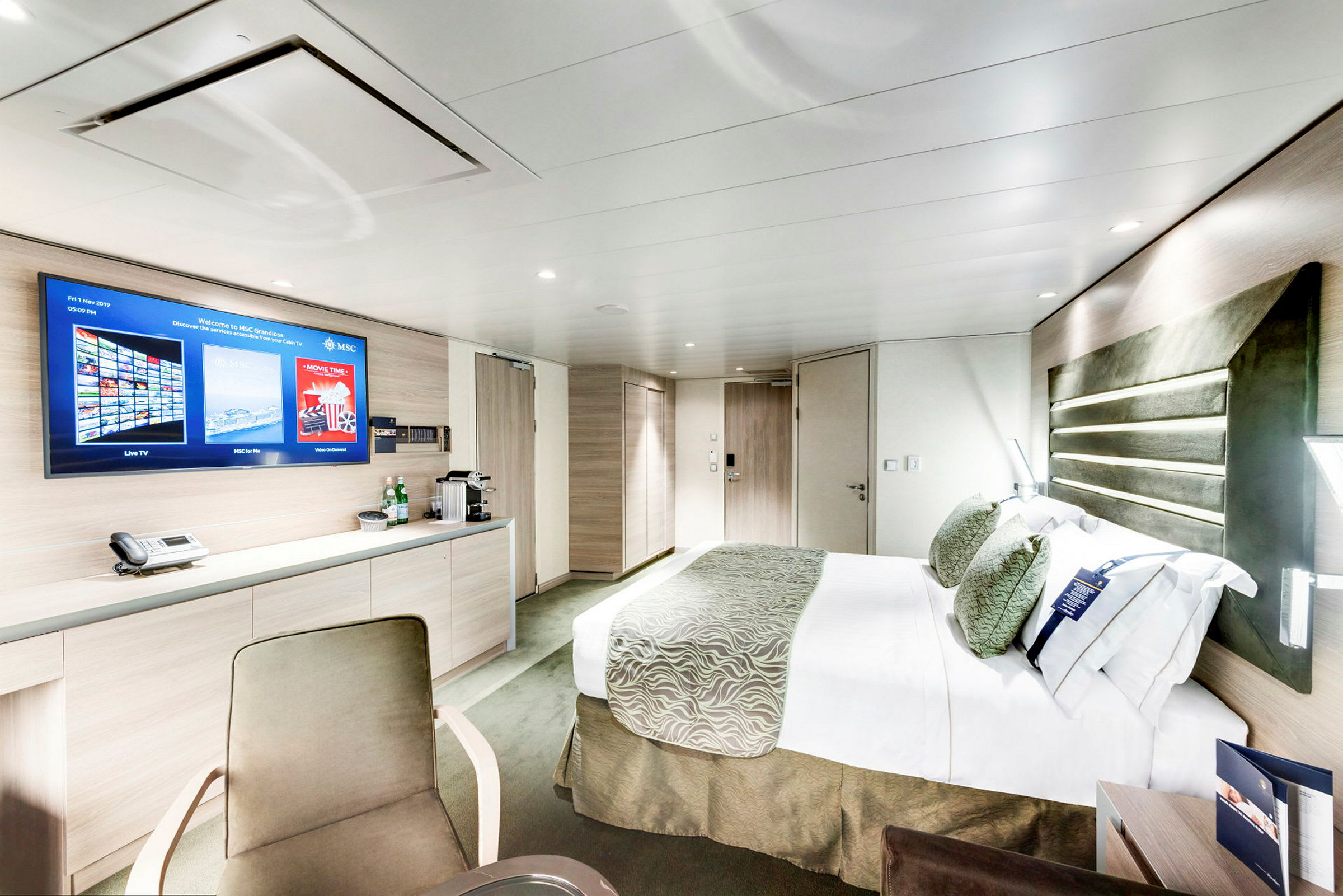Ett modernt hotellrum med säng, skrivbord och TV. (AI-genererad text)