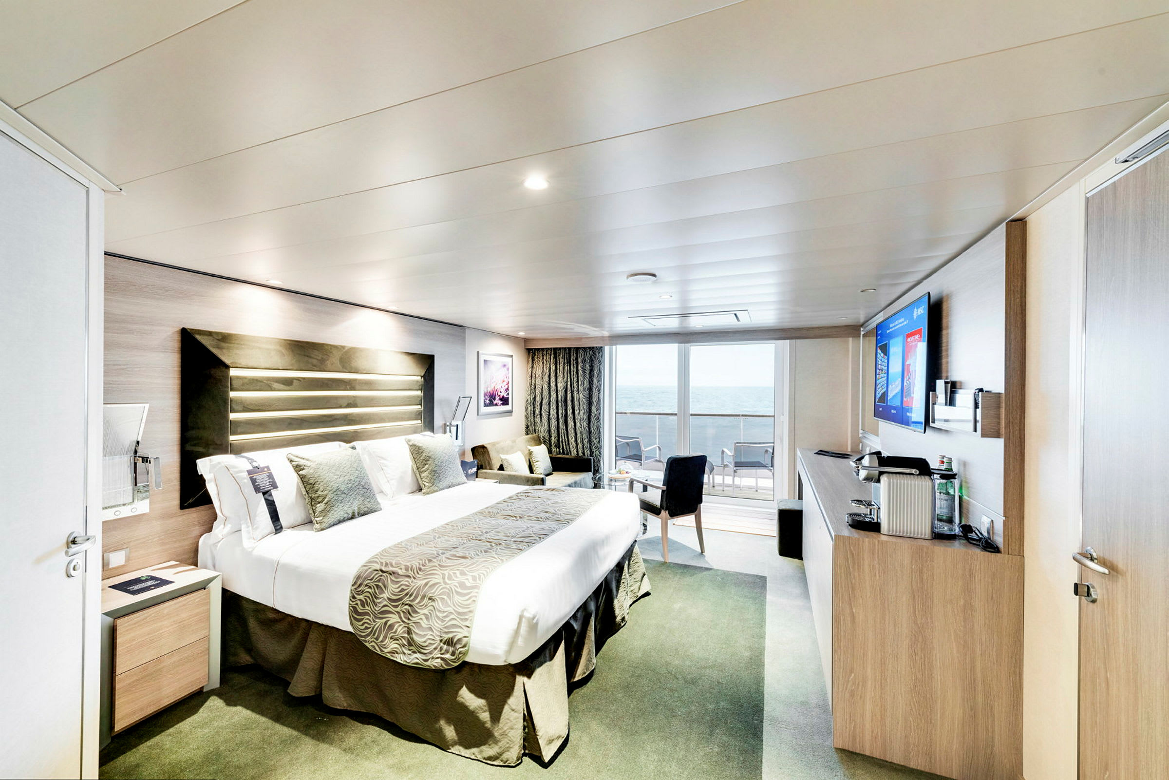 Hotellrum med dubbelsäng och utsikt mot havet från balkongen. (AI-genererad text)