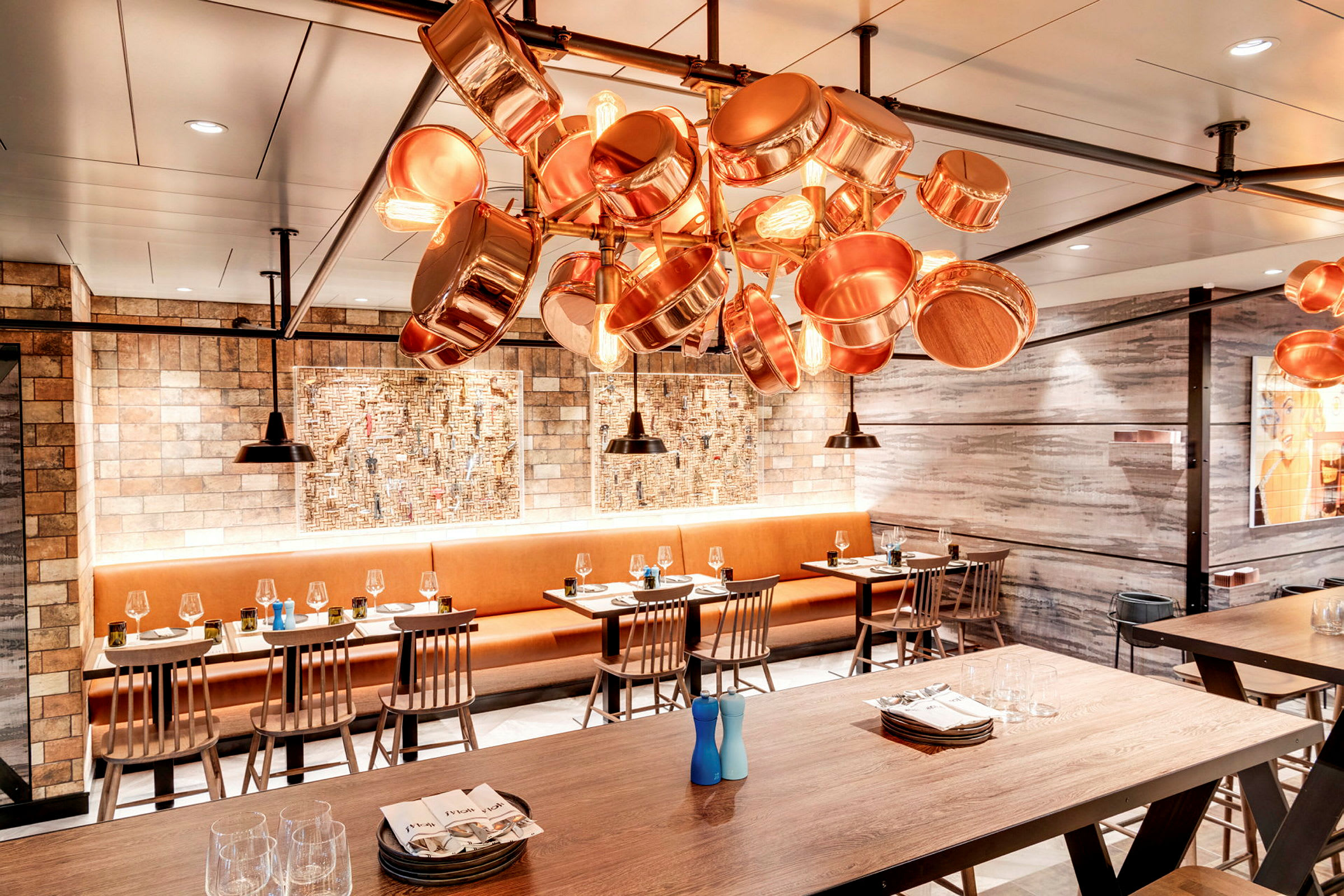 Restaurang med träbord, stolar och taklampa av kopparkärl. (AI-genererad text)