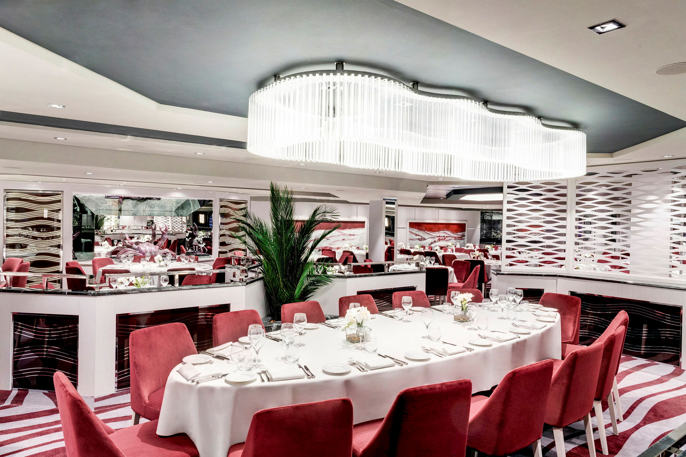 Elegant restaurang med röda stolar, vit duk och modern inredning. (AI-genererad text)