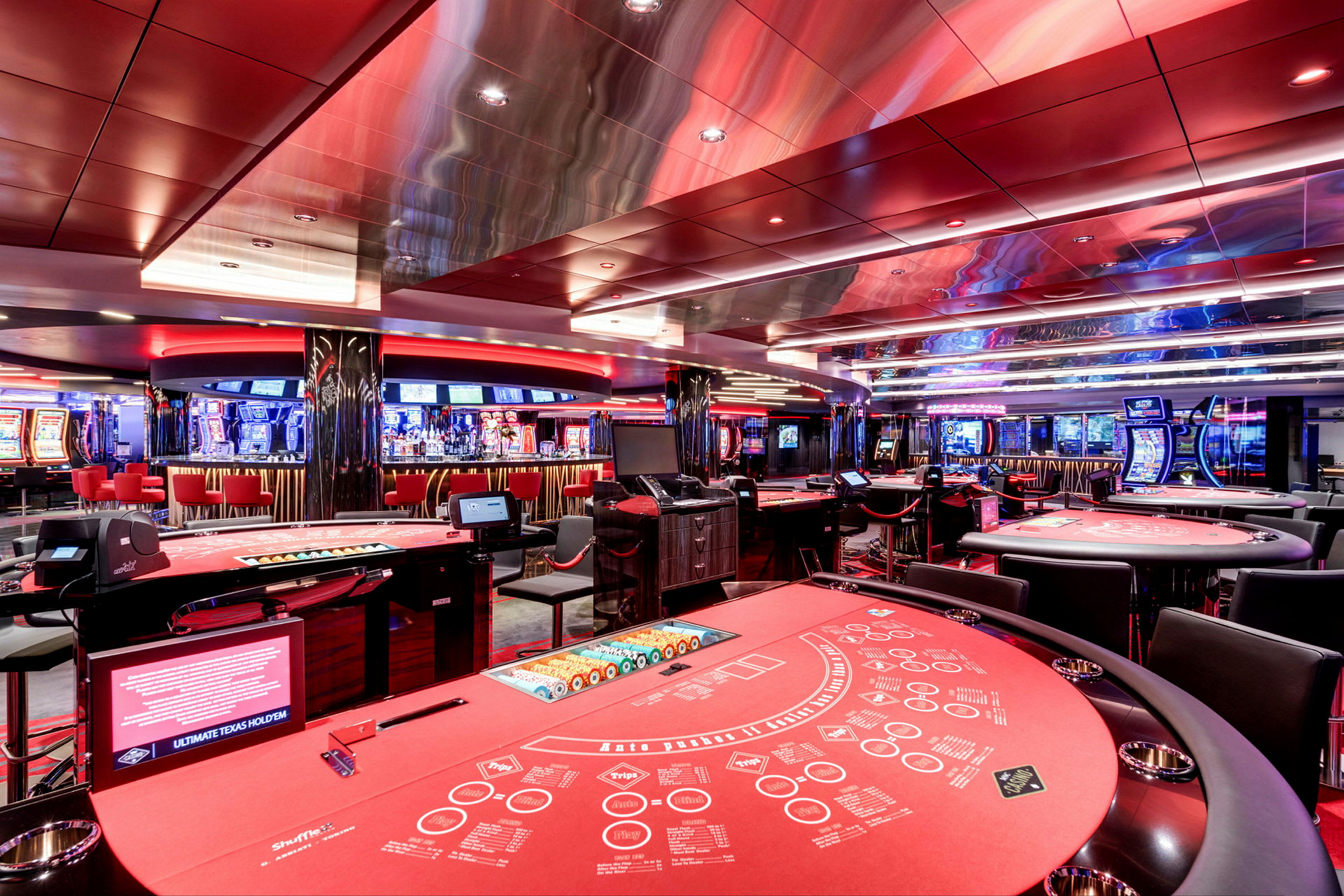 Bild av ett casino med flera bord för kortspel och spelautomater i bakgrunden. (AI-genererad text)