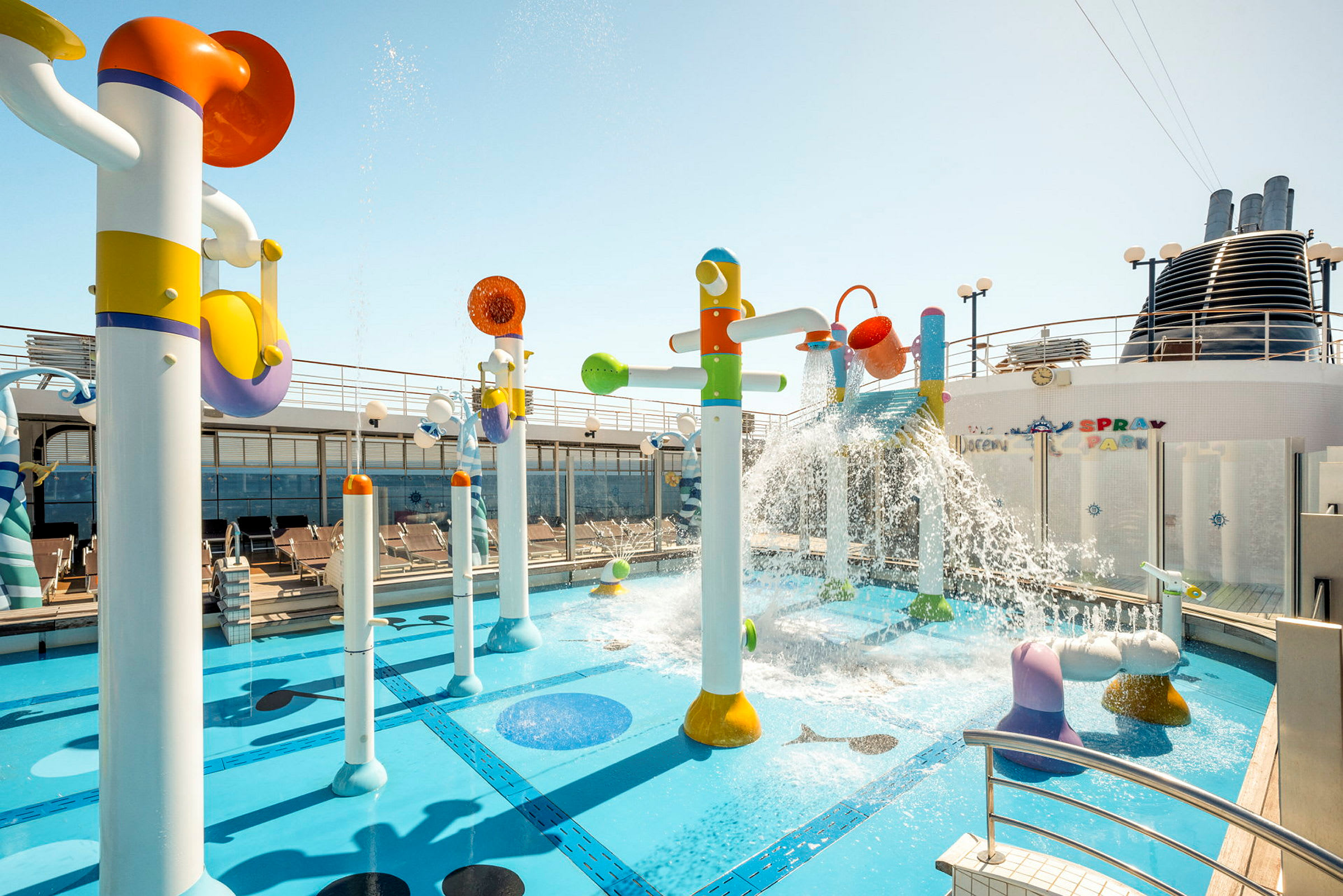 Färgglada vattenleksaker och fontäner vid en pool på ett fartygsdäck. (AI-genererad text)