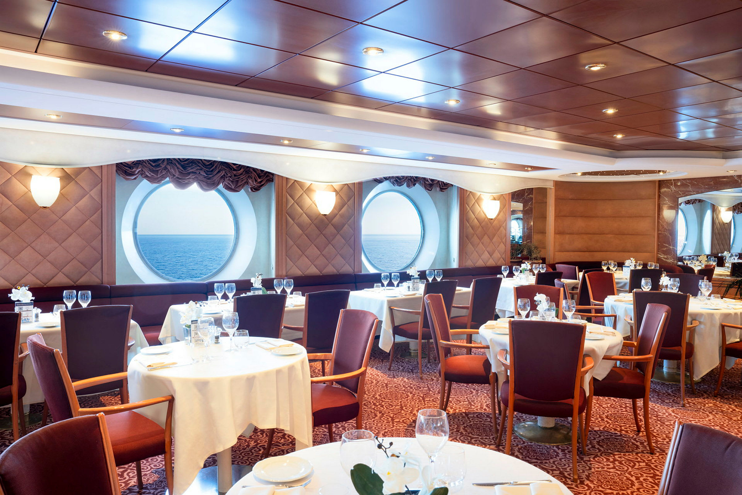 En elegant matsal med runda fönster som vetter mot havet. (AI-genererad text)