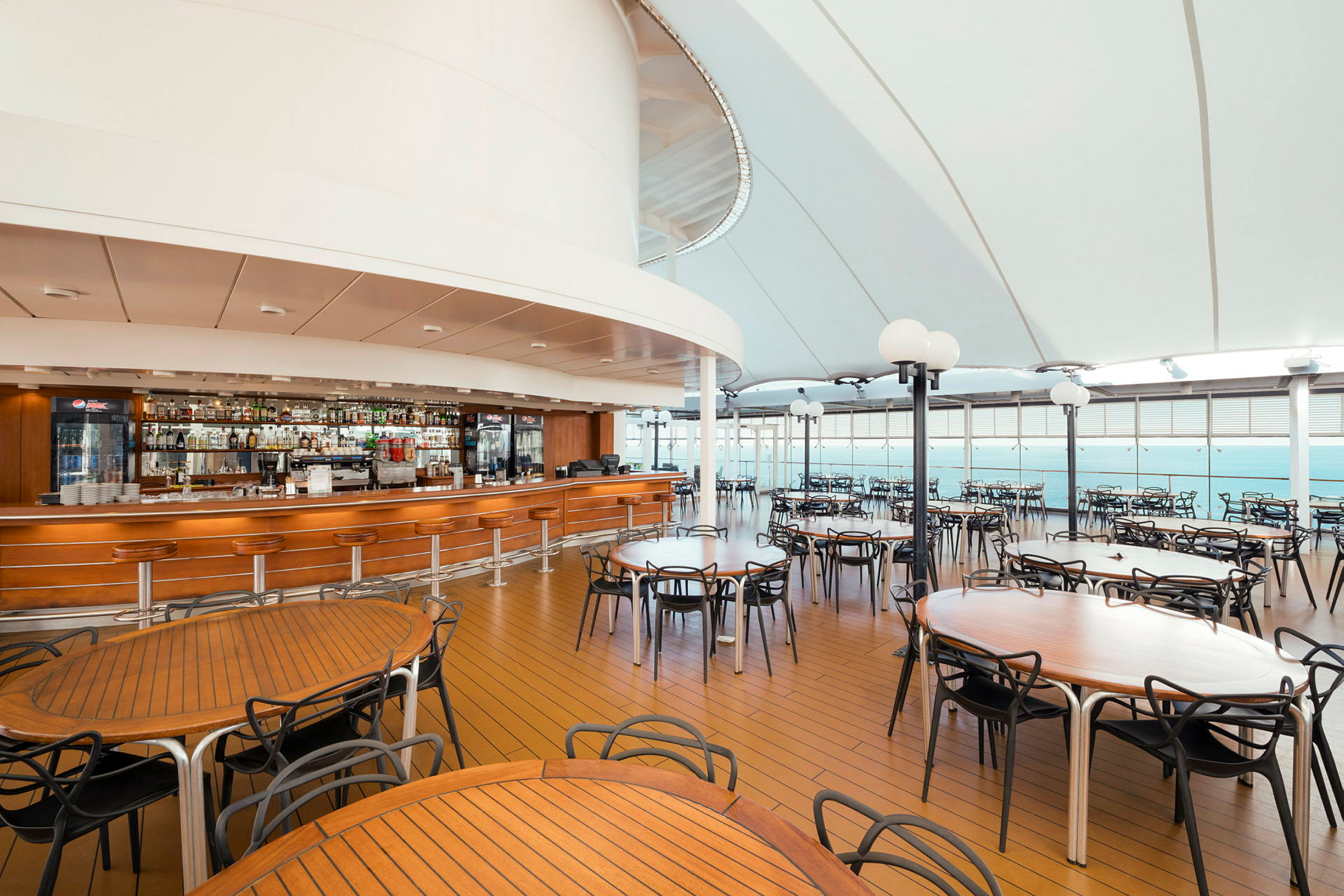 En täckt restaurang med träbord, stolar och en bar. (AI-genererad text)