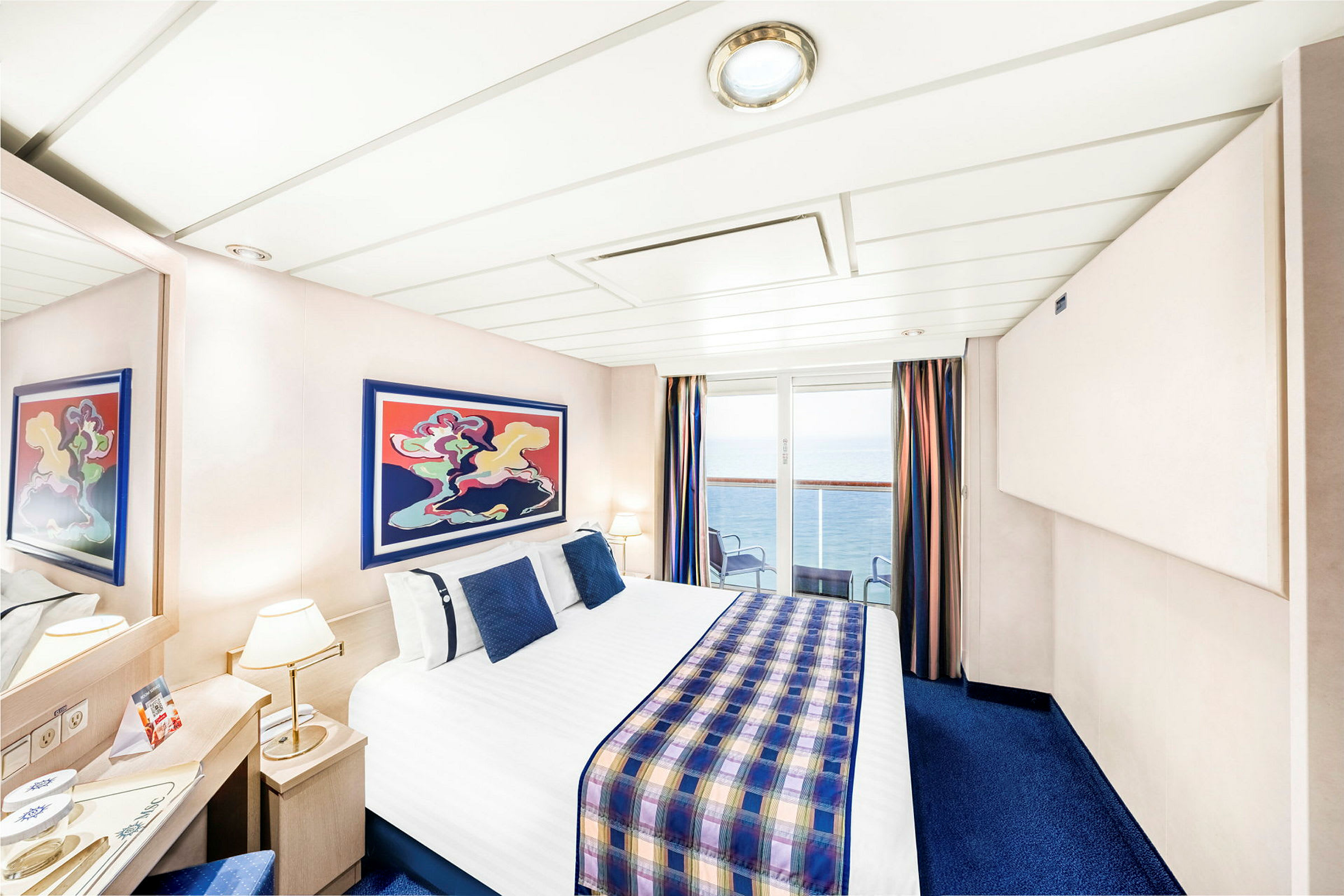 Ett hotellrum med en dubbelsäng och havsutsikt genom glasdörrar. (AI-genererad text)