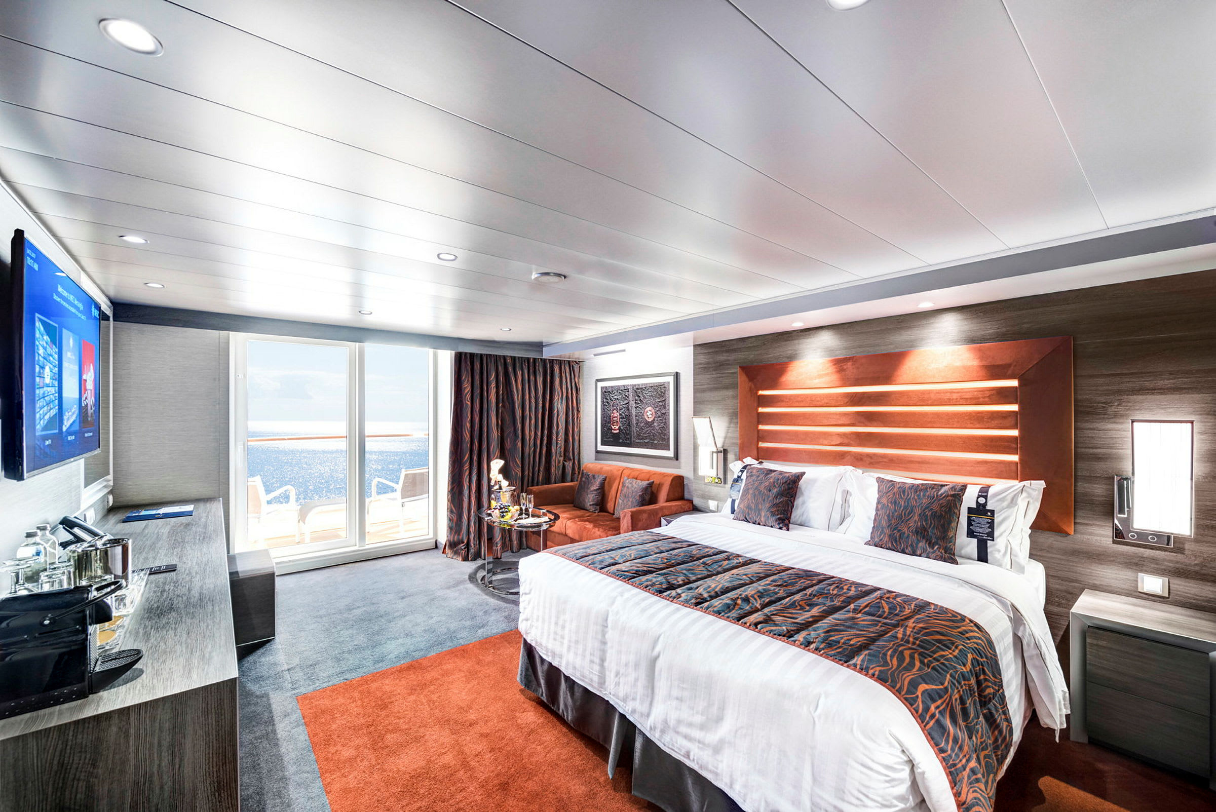 Hotellrum med stor säng, sittgrupp och balkong. (AI-genererad text)
