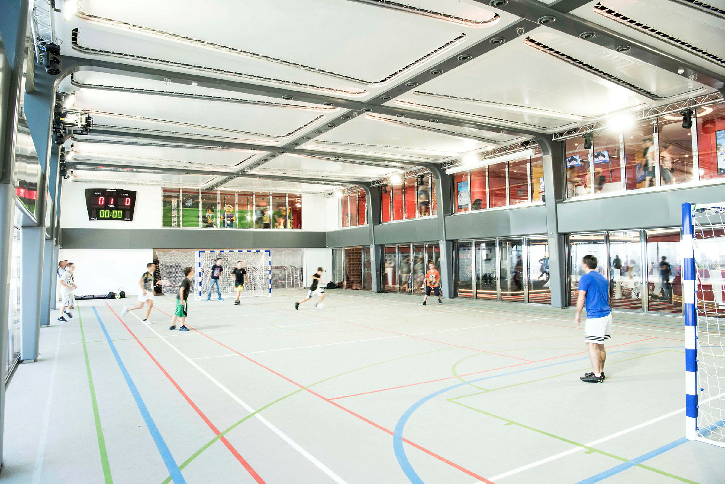 En inomhus sporthall där människor spelar fotboll. (AI-genererad text)