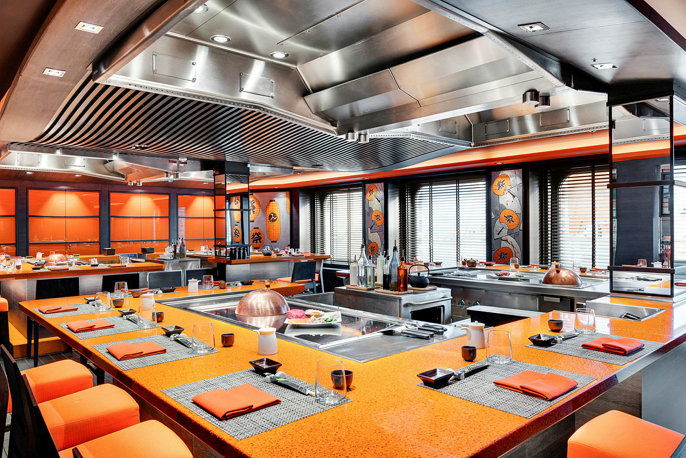 Ett restaurangområde med orange bordsytor, dekorerat med asiatisk konst och stil. (AI-genererad text)