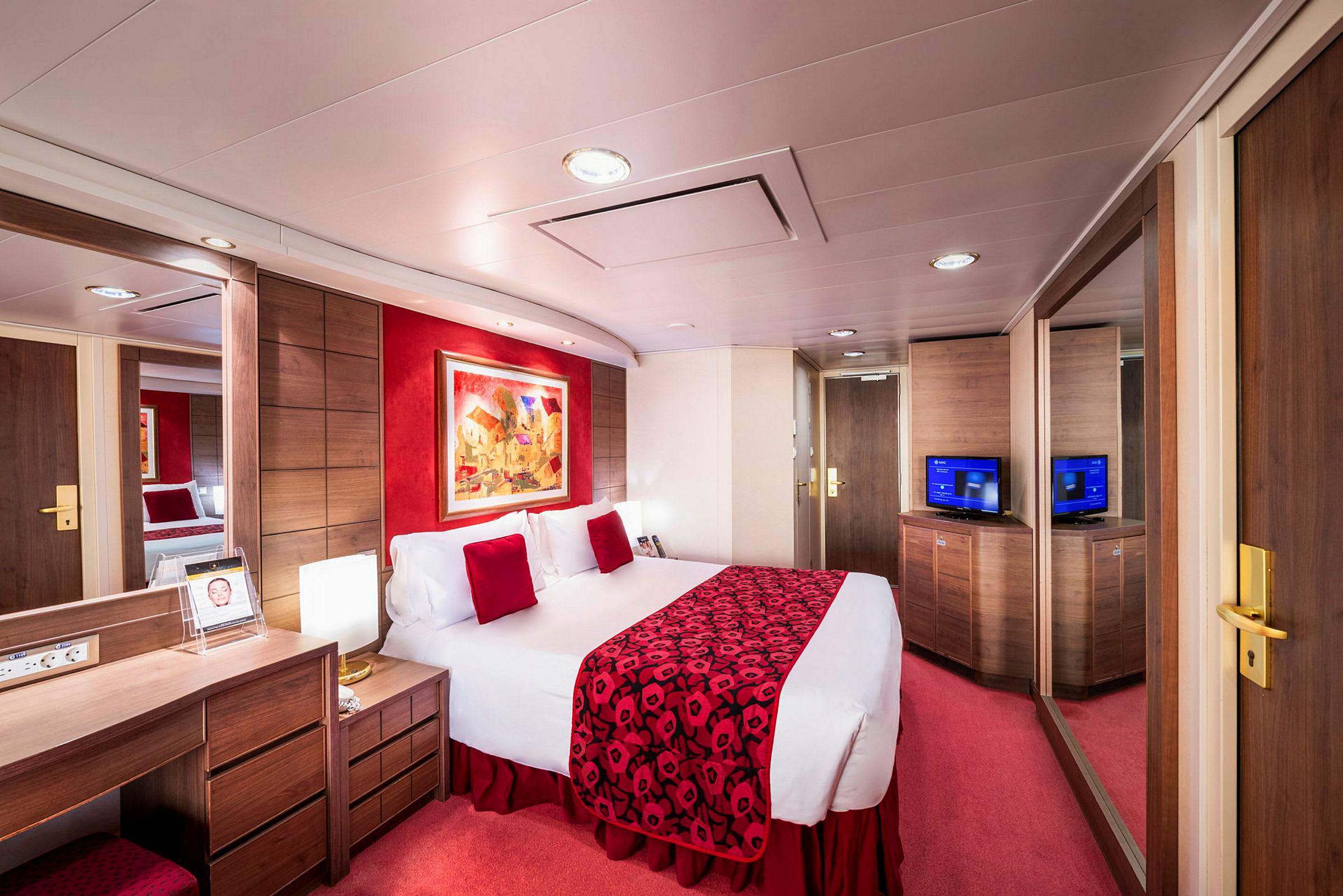 Ett hotellrum med en stor säng, röd inredning och en TV. (AI-genererad text)