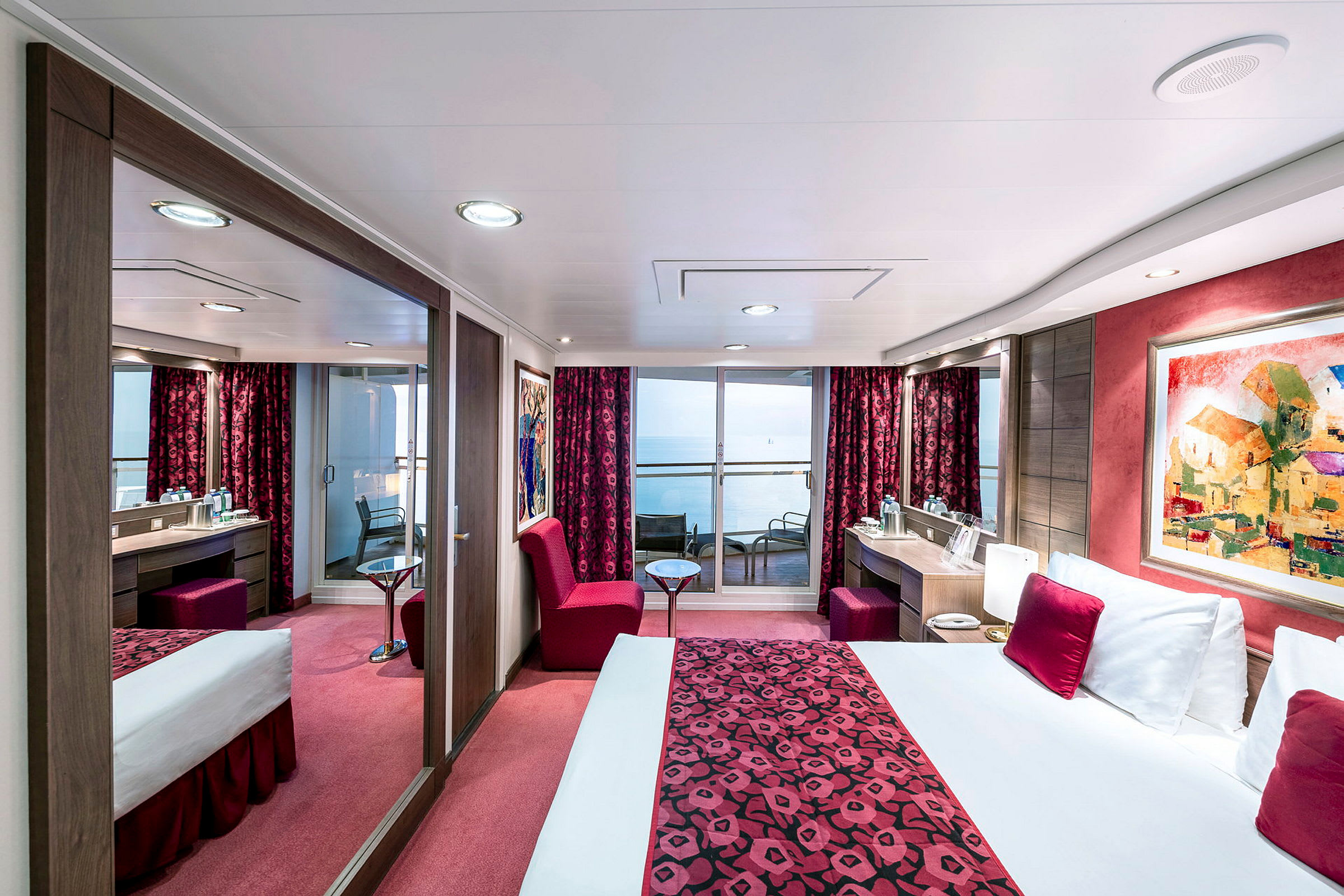 Ett hotellrum med havsutsikt, inrett med röda textilier och moderna möbler. (AI-genererad text)