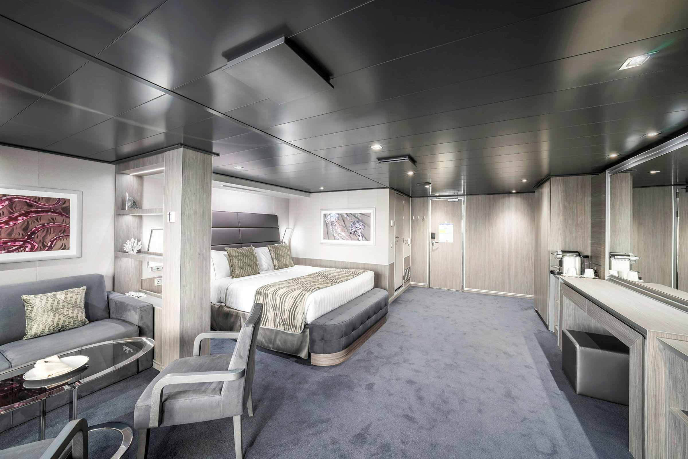 Bild av ett modernt hotellrum med en dubbelsäng, sittplats, bord och spegel. (AI-genererad text)