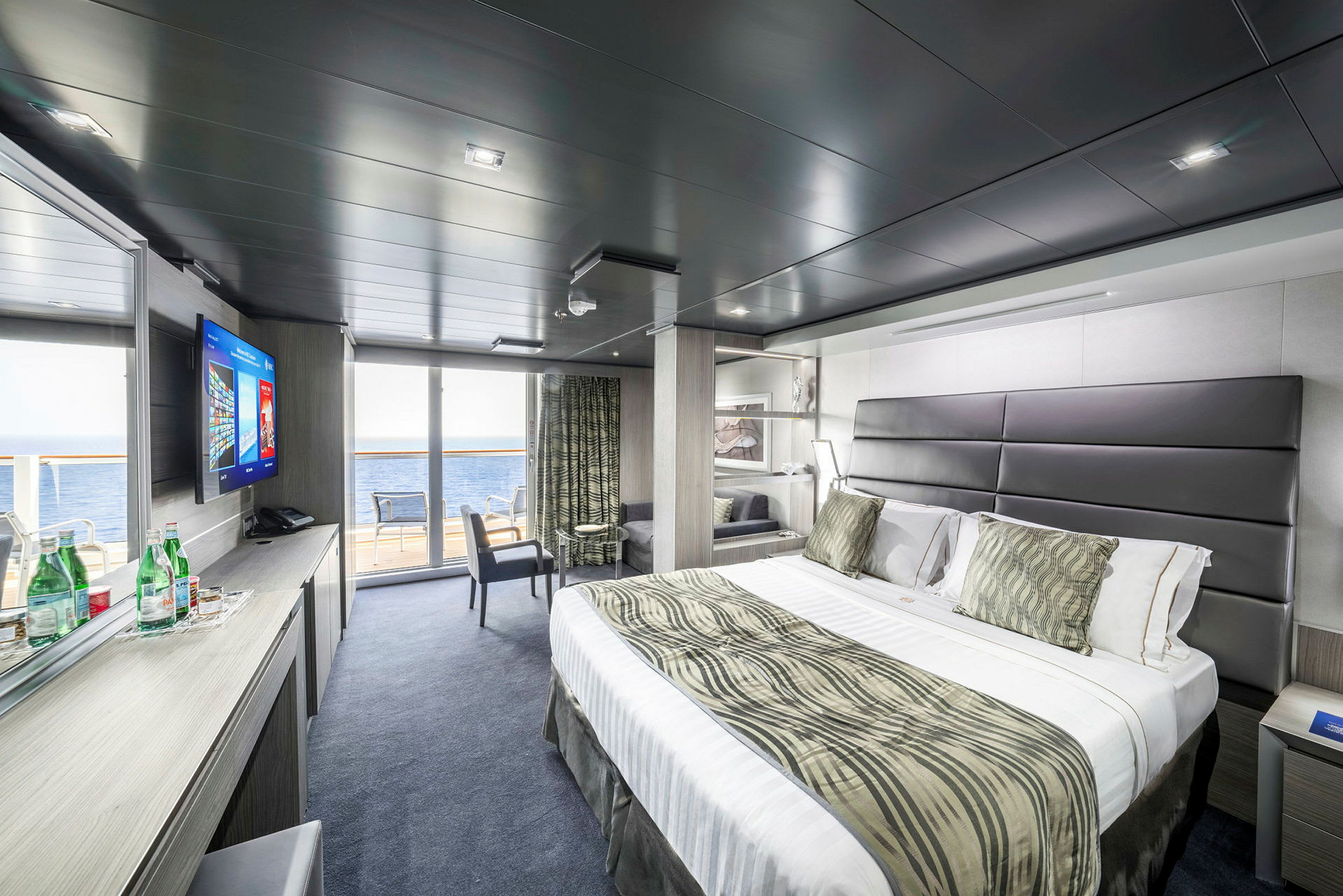 Moderna hotellrum med stor säng, sittplats och havsutsikt. (AI-genererad text)