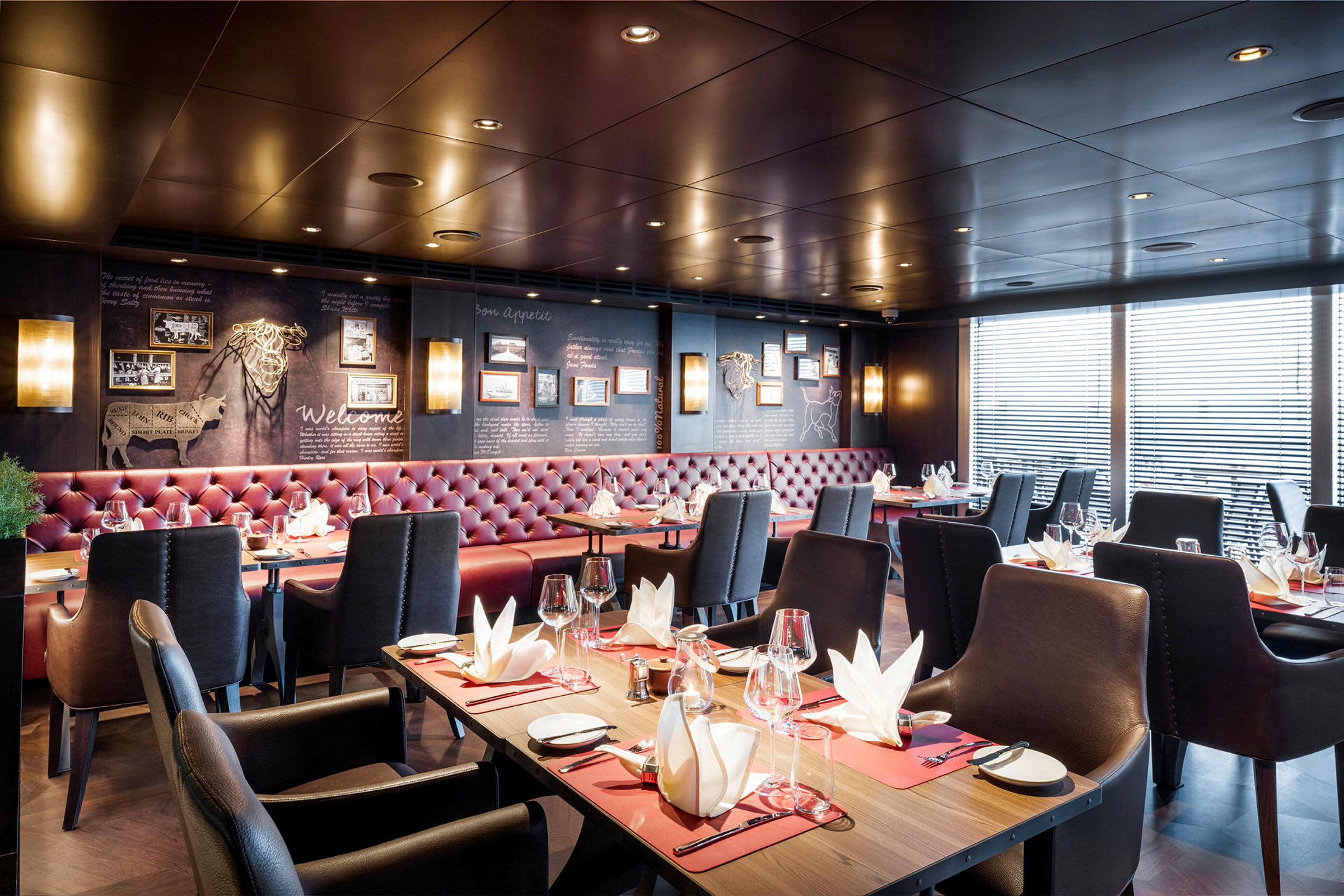 Interiör av en elegant restaurang med dukade bord och röda stoppade soffor. (AI-genererad text)