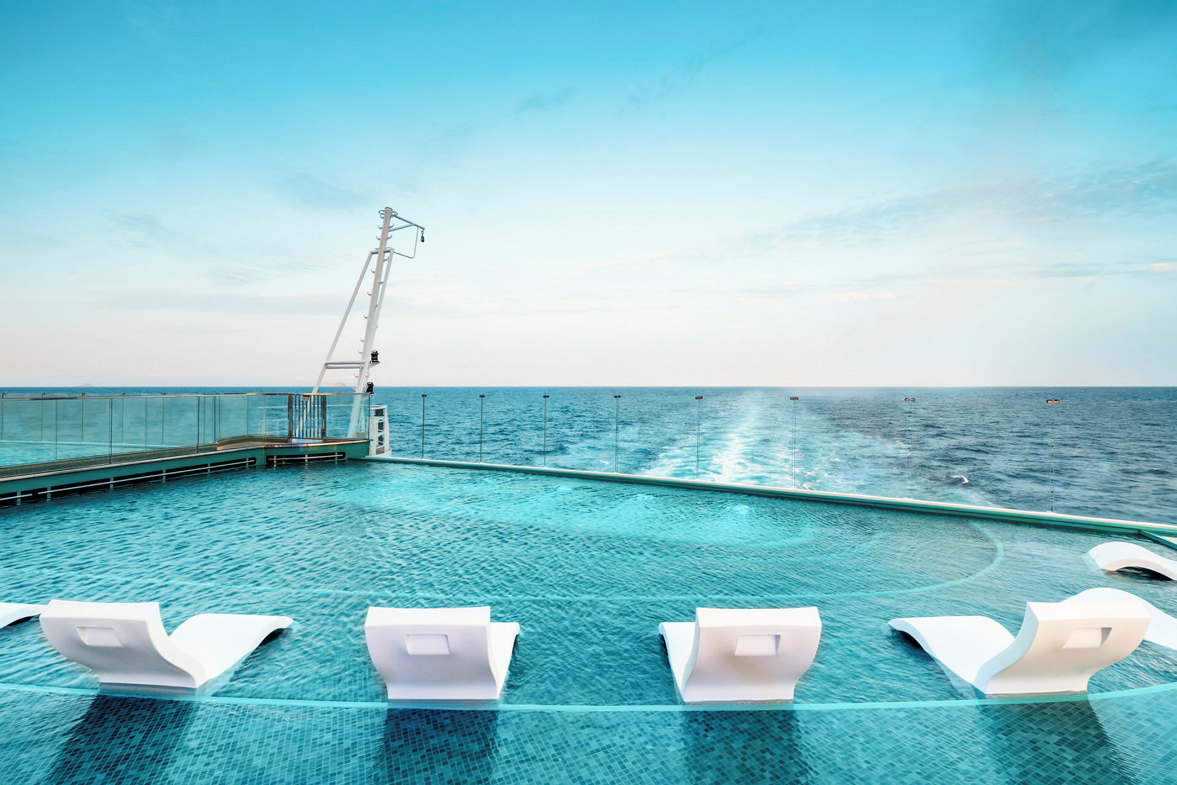 Pool med vita solstolar vid havet. (AI-genererad text)