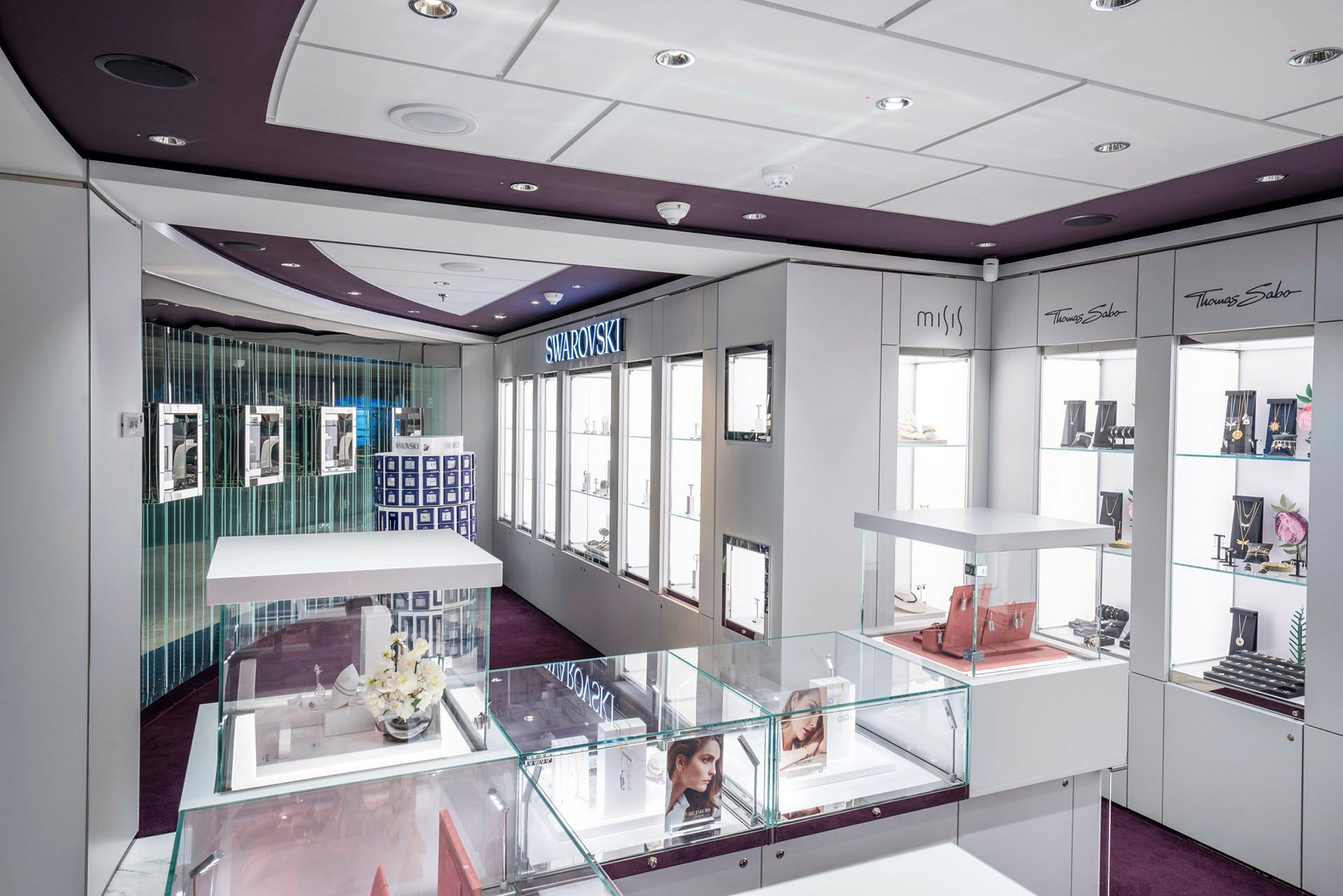 Ett modernt smyckesbutikinteriör med glasmontrar och varumärken som Swarovski och Thomas Sabo. (AI-genererad text)