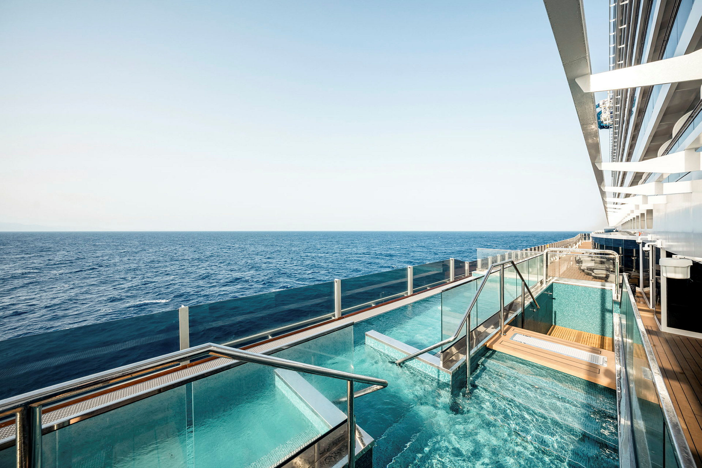 En pool med glasräcken på ett fartyg med havet i bakgrunden. (AI-genererad text)