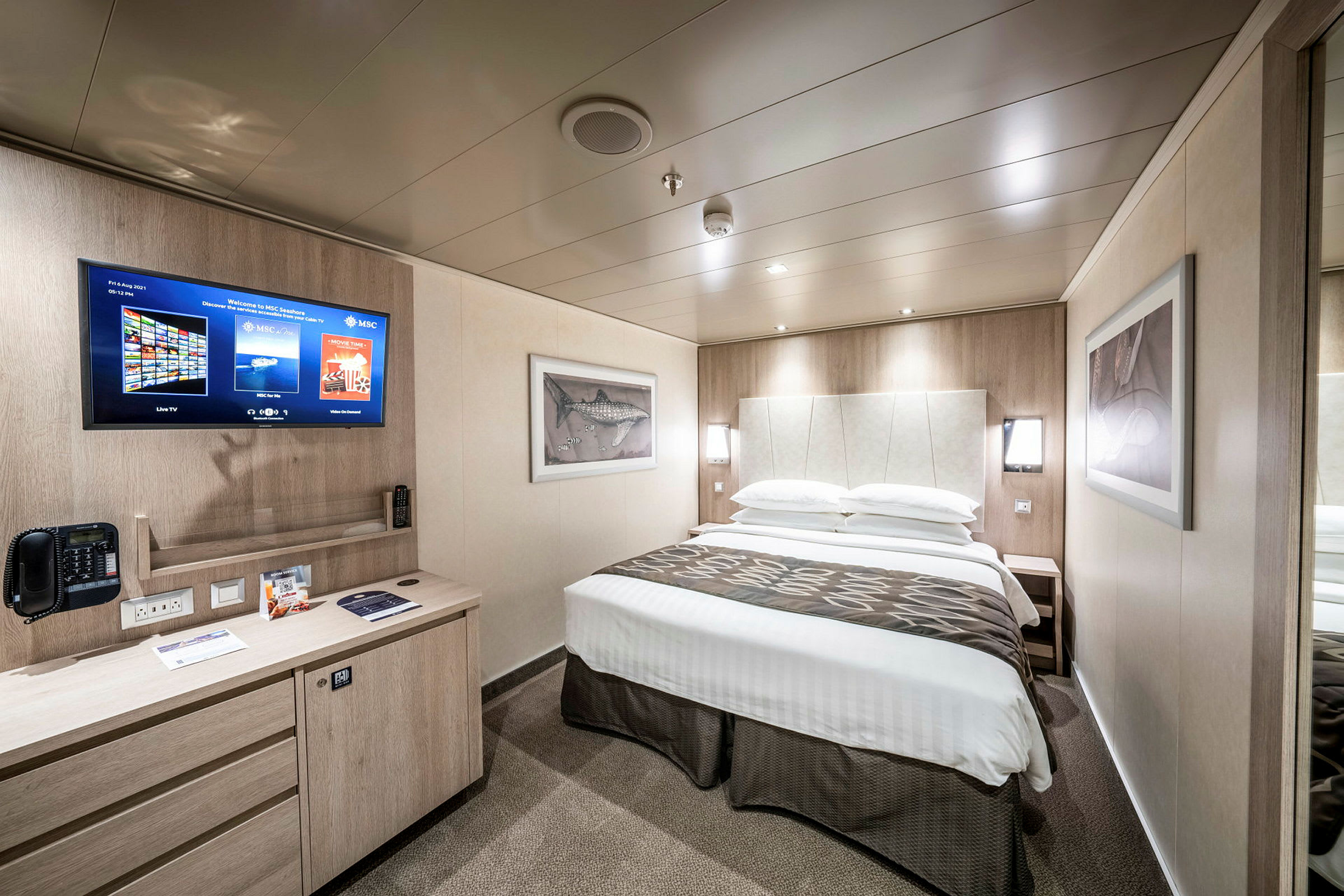 Ett hotellrum med en dubbelsäng, en TV på väggen och en skrivbordsyta. (AI-genererad text)