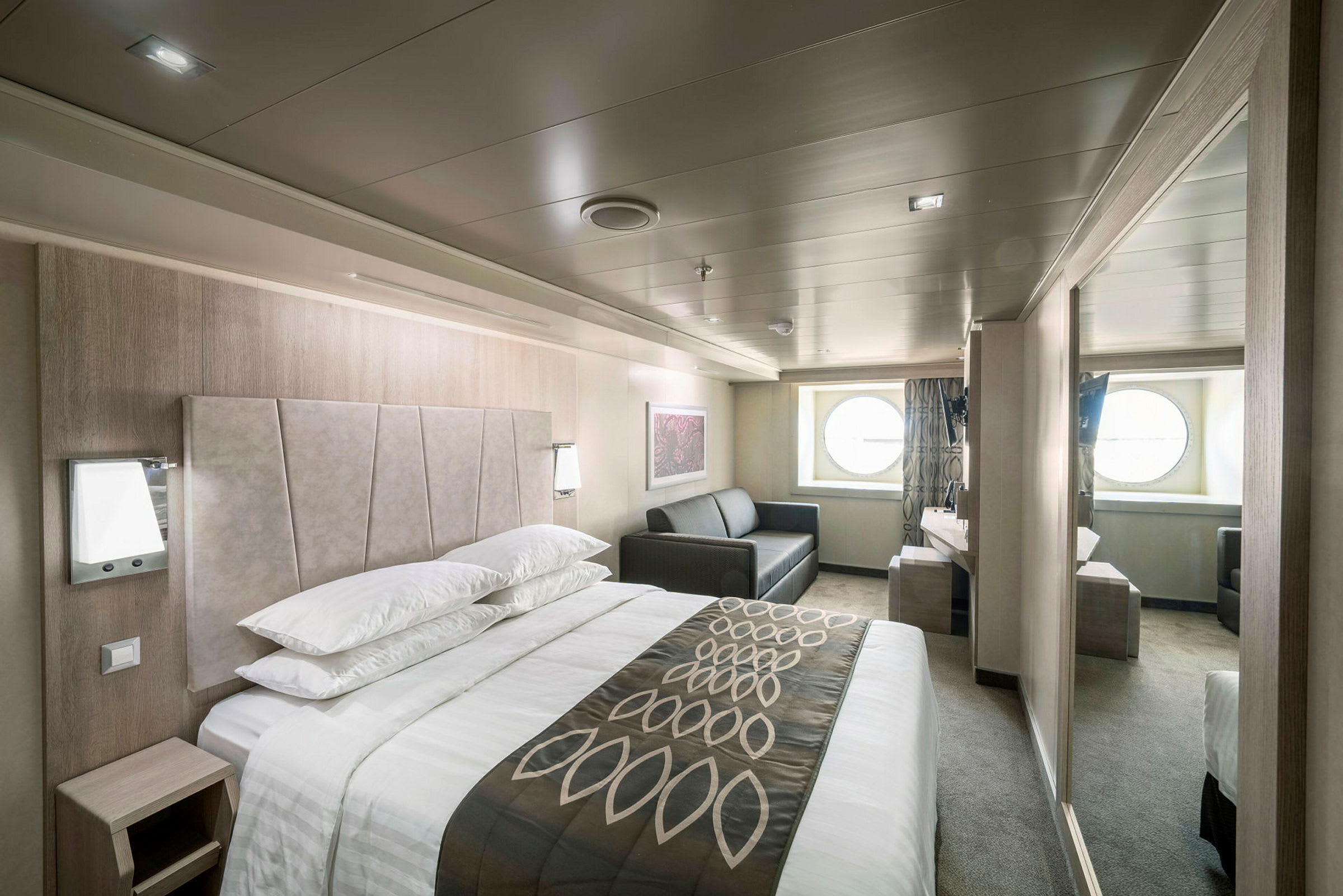 Ett rymligt hotellrum med en stor säng, en soffa och fönster med runda former. (AI-genererad text)