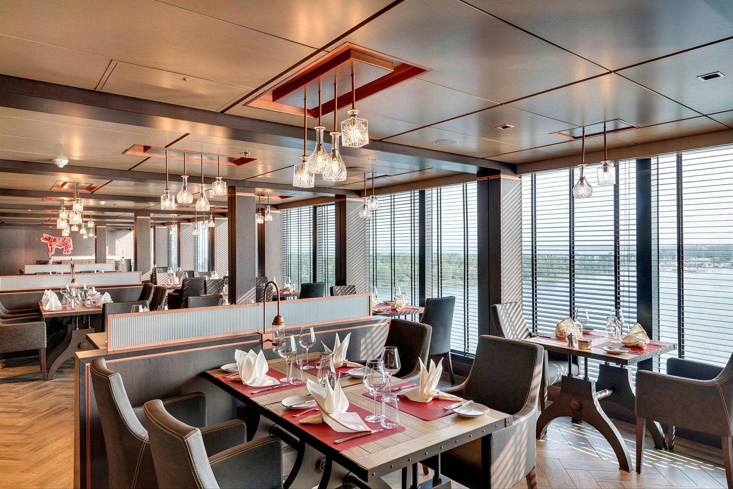 Restaurang med bord, stolar och servetter, stora fönster med utsikt. (AI-genererad text)