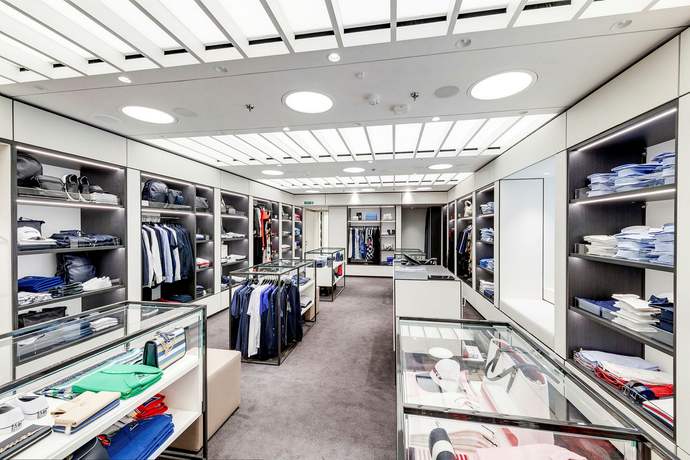 En inredd klädbutik med hyllor, glasmontrar och kläder. (AI-genererad text)