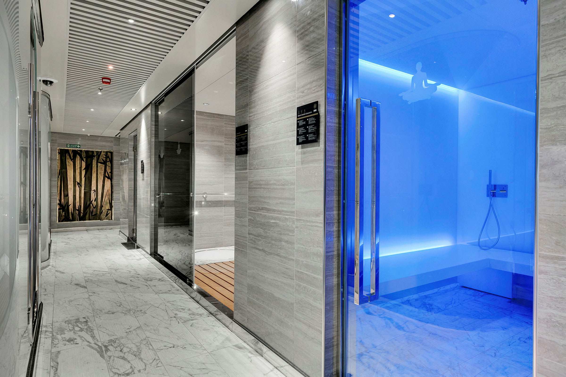 Modern spa-interiör med glasdörrar, marmorgolv och blå belysning. (AI-genererad text)