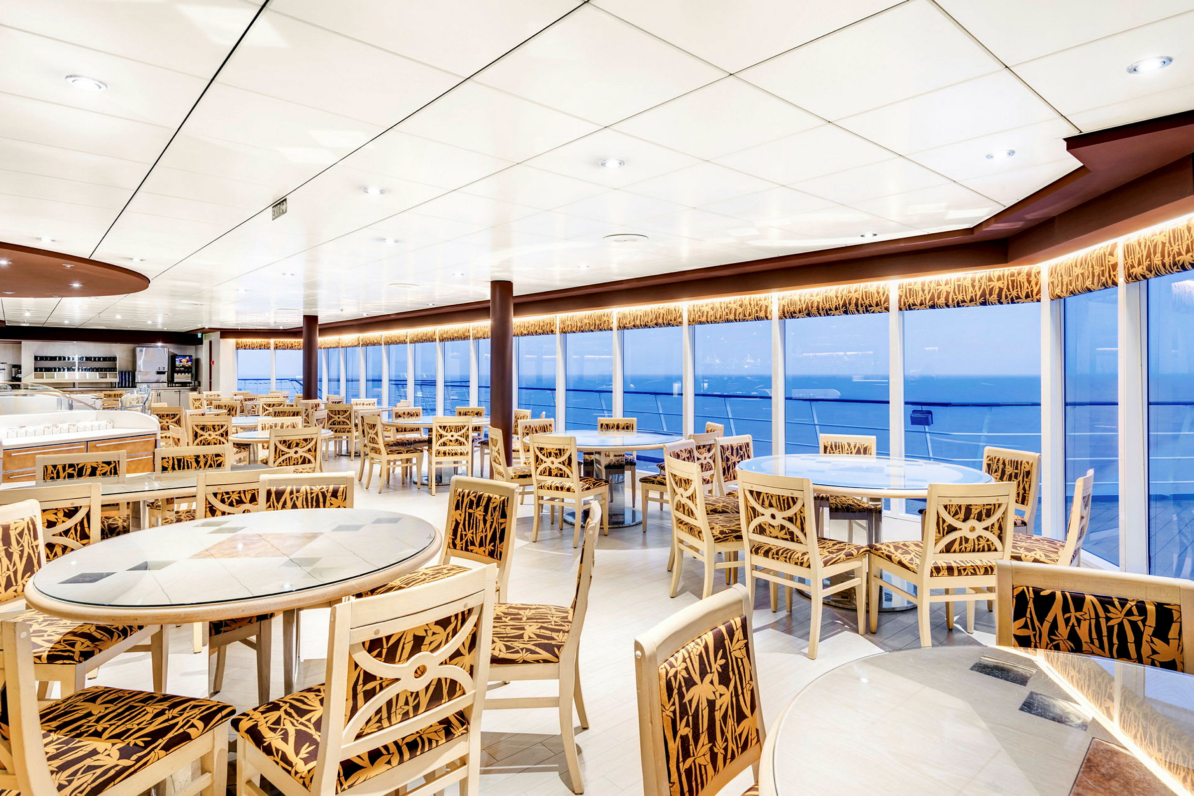 Ett restaurangområde med bord och stolar framför stora fönster. (AI-genererad text)