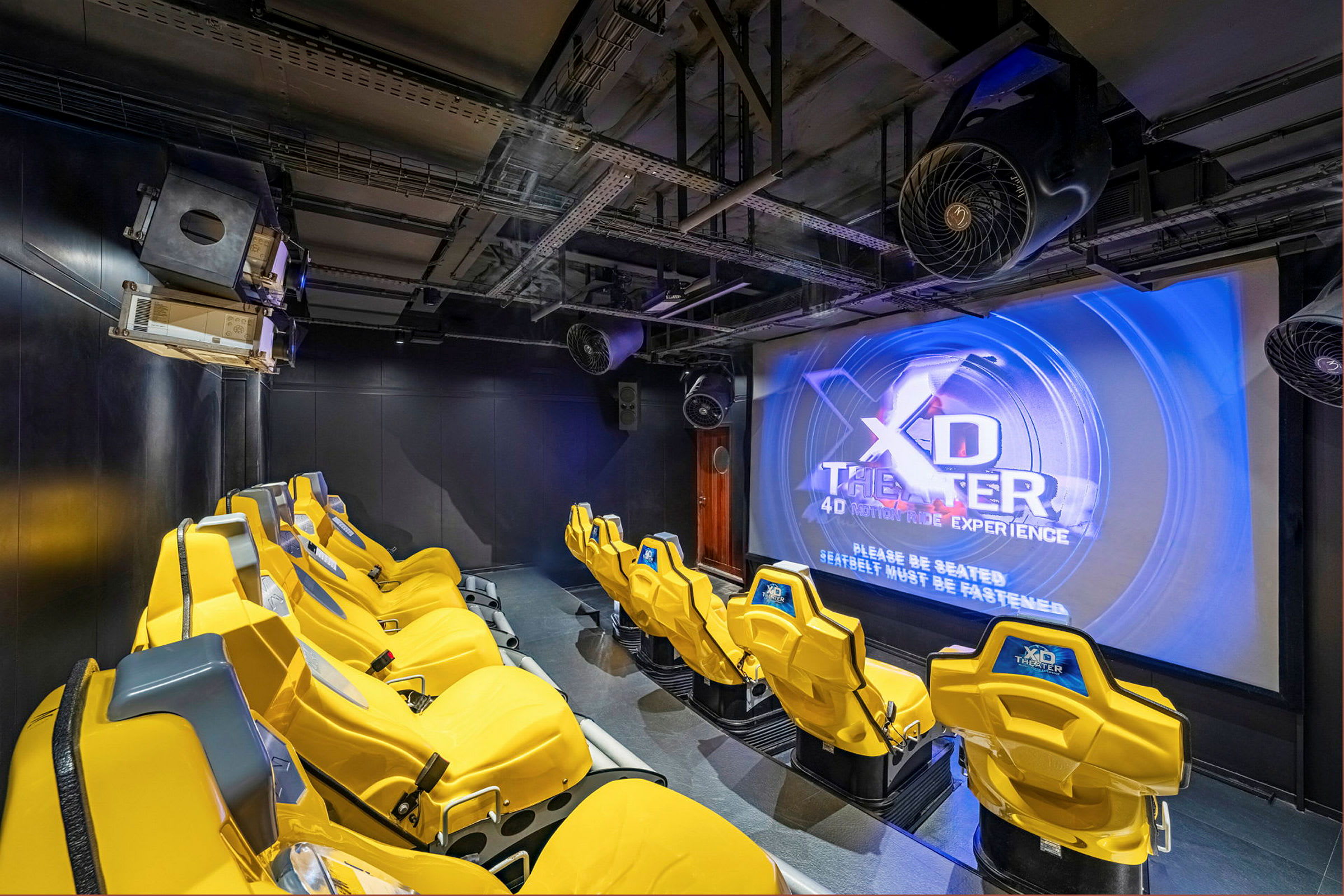 Interiör av en 4D-biograf med gula stolar och en stor skärm. (AI-genererad text)