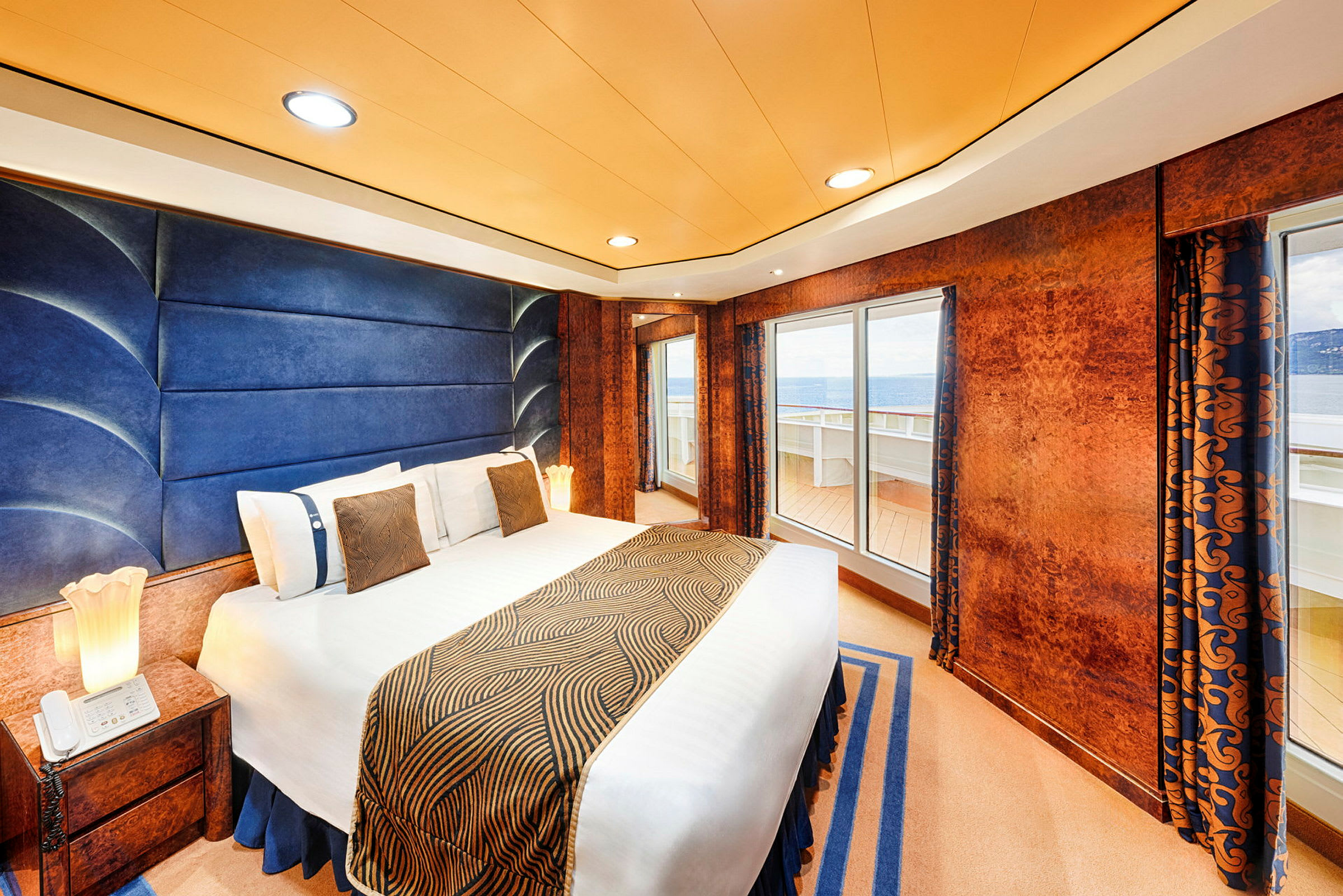 Ett hotellrum med en stor säng, blå och orange dekor samt utsikt genom fönstret. (AI-genererad text)