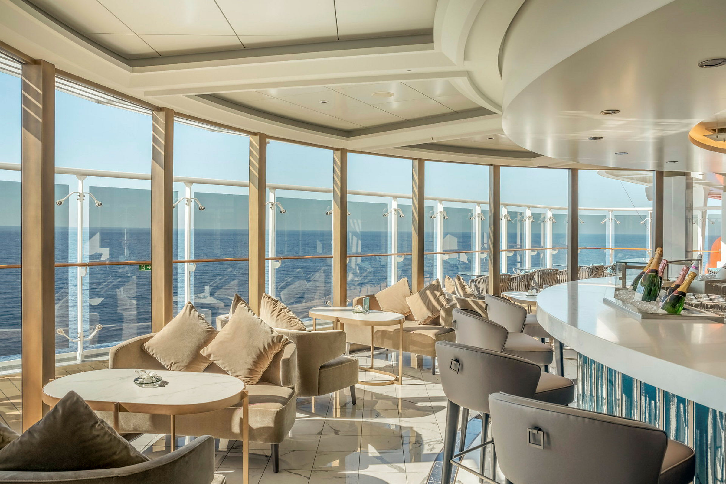 En elegant lounge med sittplatser och bord vid stora fönster med utsikt över havet. (AI-genererad text)