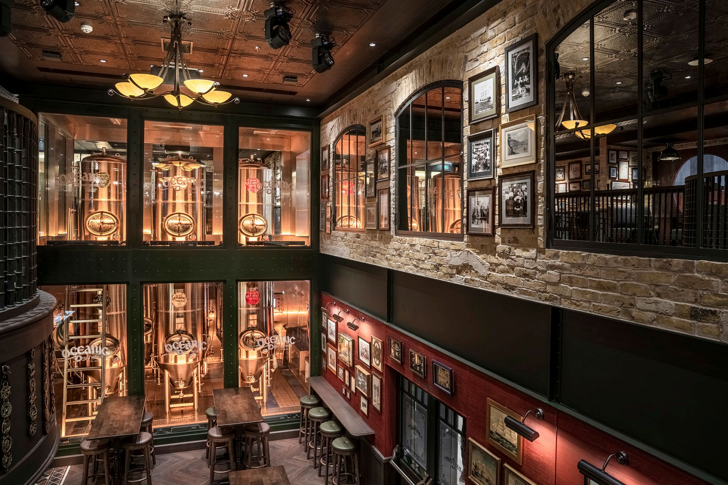 Inre av en bar med bryggeritankar bakom glas och väggar dekorerade med tavlor. (AI-genererad text)