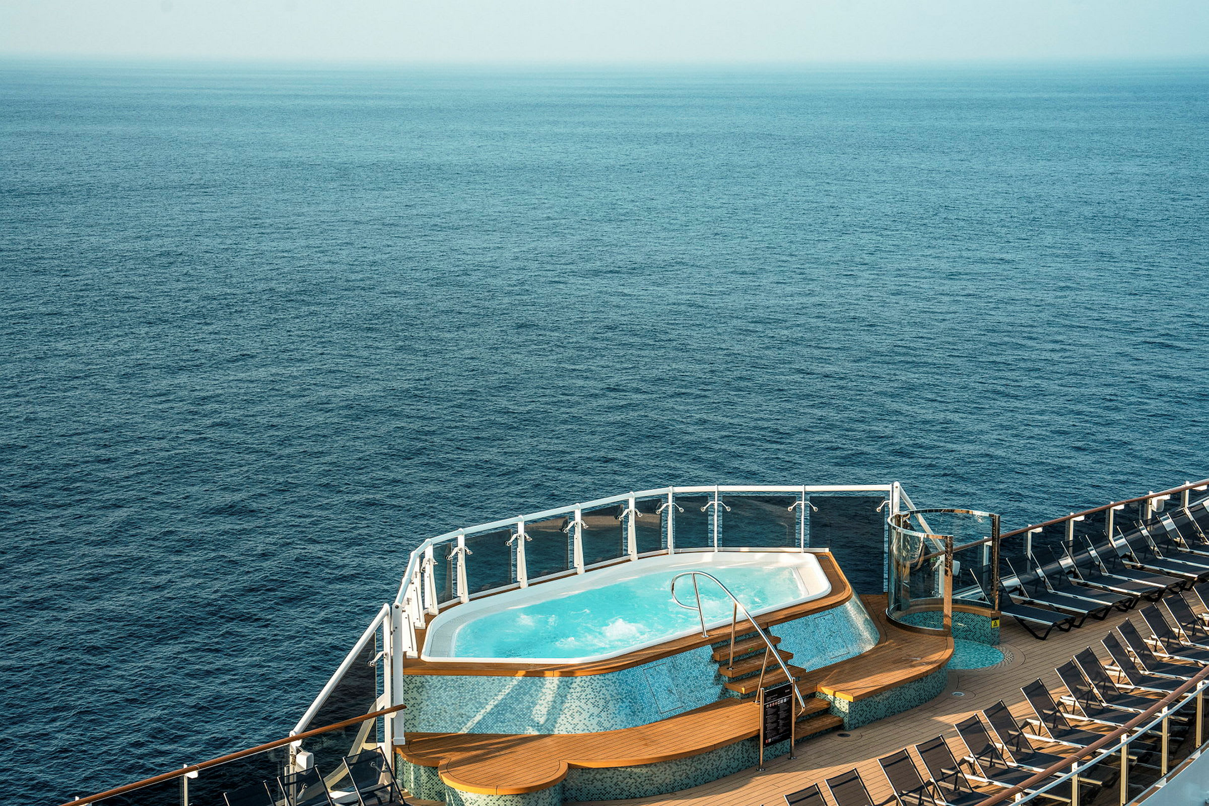 En jacuzzi på däck med utsikt över havet. (AI-genererad text)