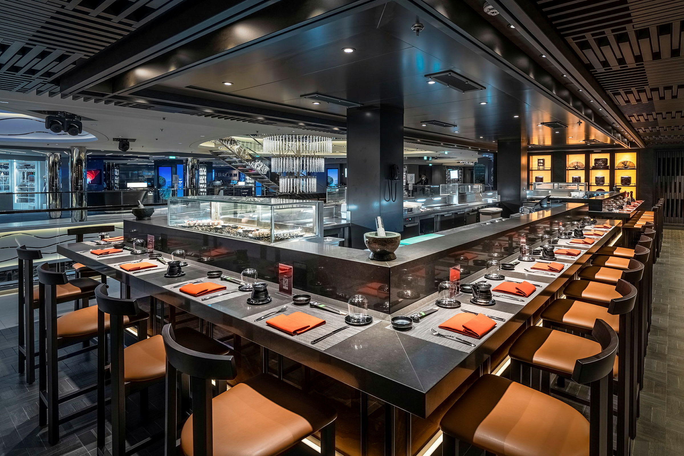 Interiör av en restaurang med en bardisk som har sittplatser och bord dukade med servetter samt en matserveringsdisk. (AI-genererad text)