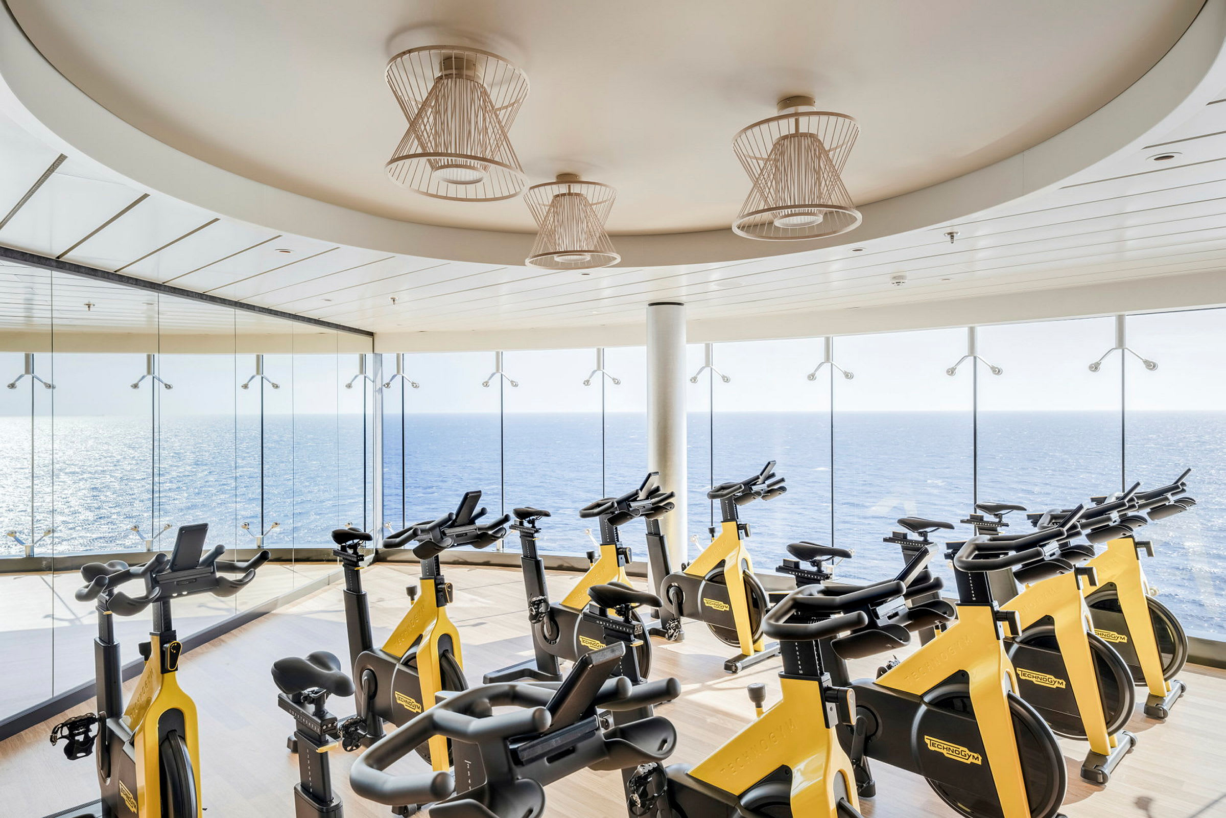 Elliptiska träningsmaskiner i ett gym med fönster mot havet. (AI-genererad text)