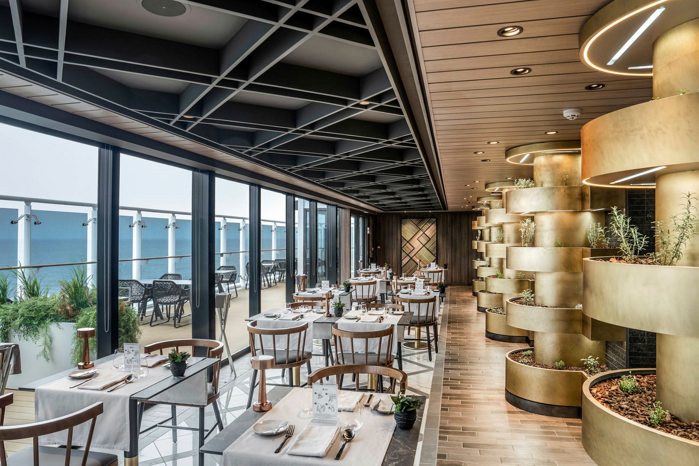 En restaurang med bord och stolar nära stora fönster, utitäppad med växter och modern inredning. (AI-genererad text)