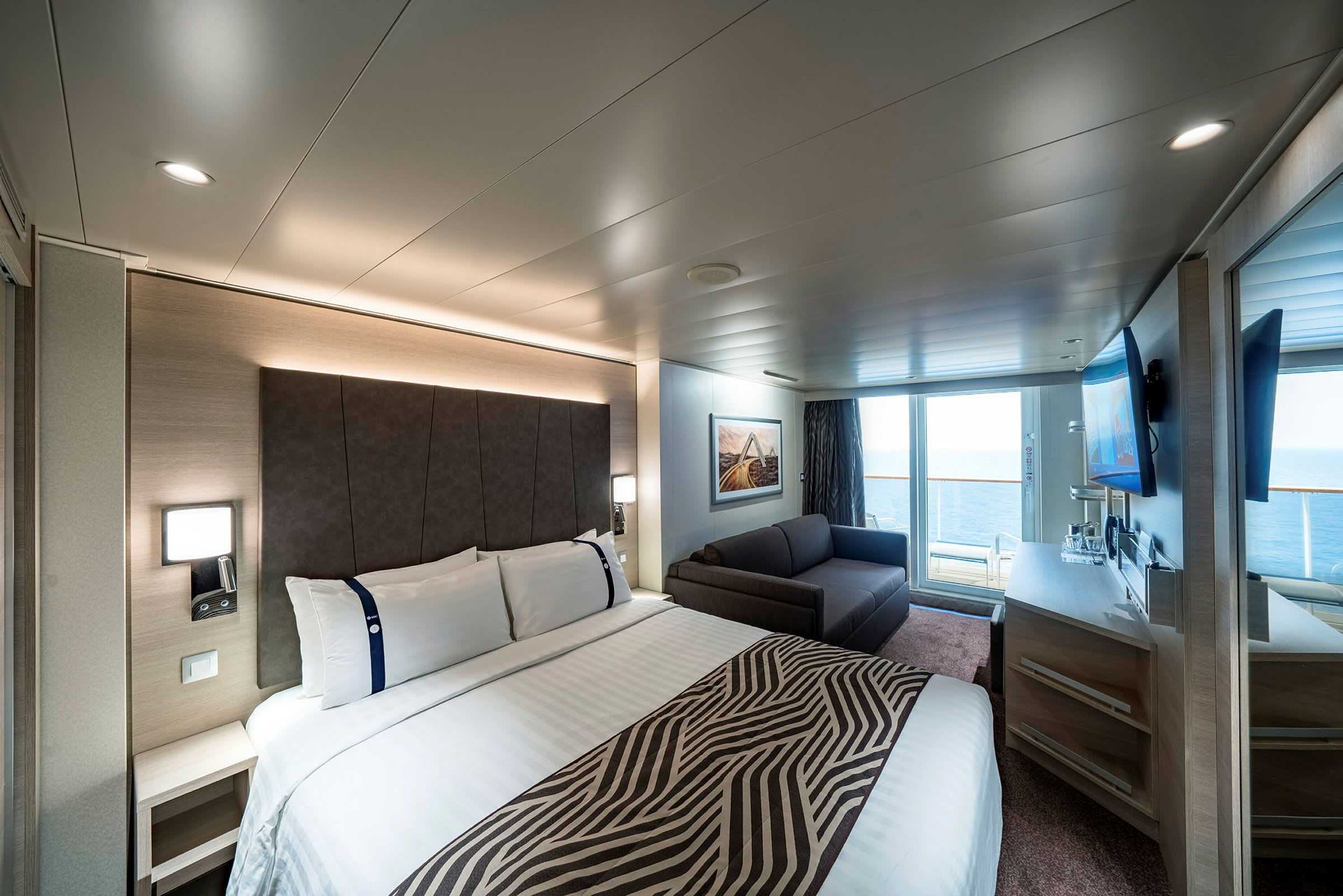 Bild av ett hotellrum med en stor säng, soffa, skrivbord och balkong. (AI-genererad text)