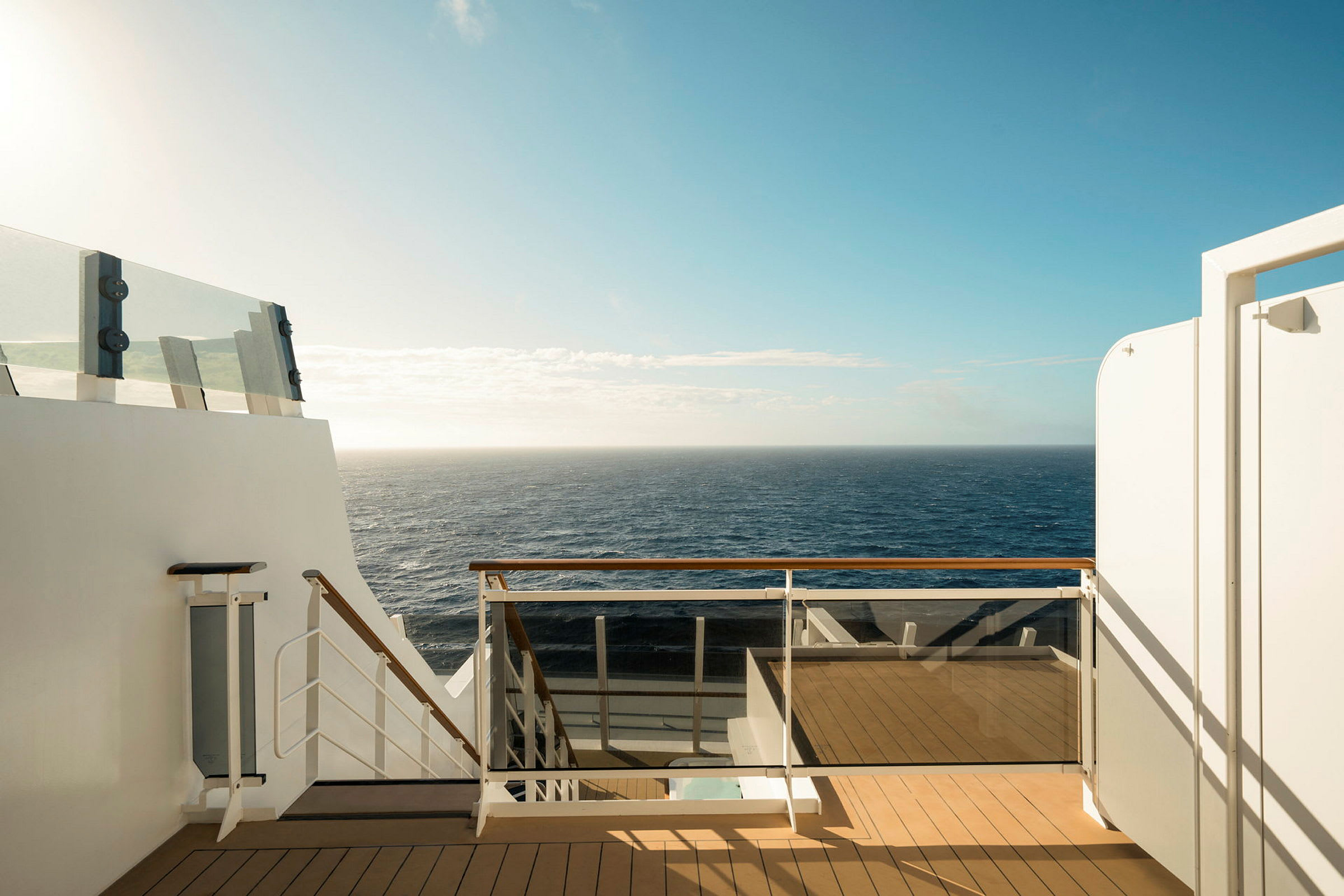 Utsikt från en däck med trappor och räcke mot havet under klar himmel. (AI-genererad text)