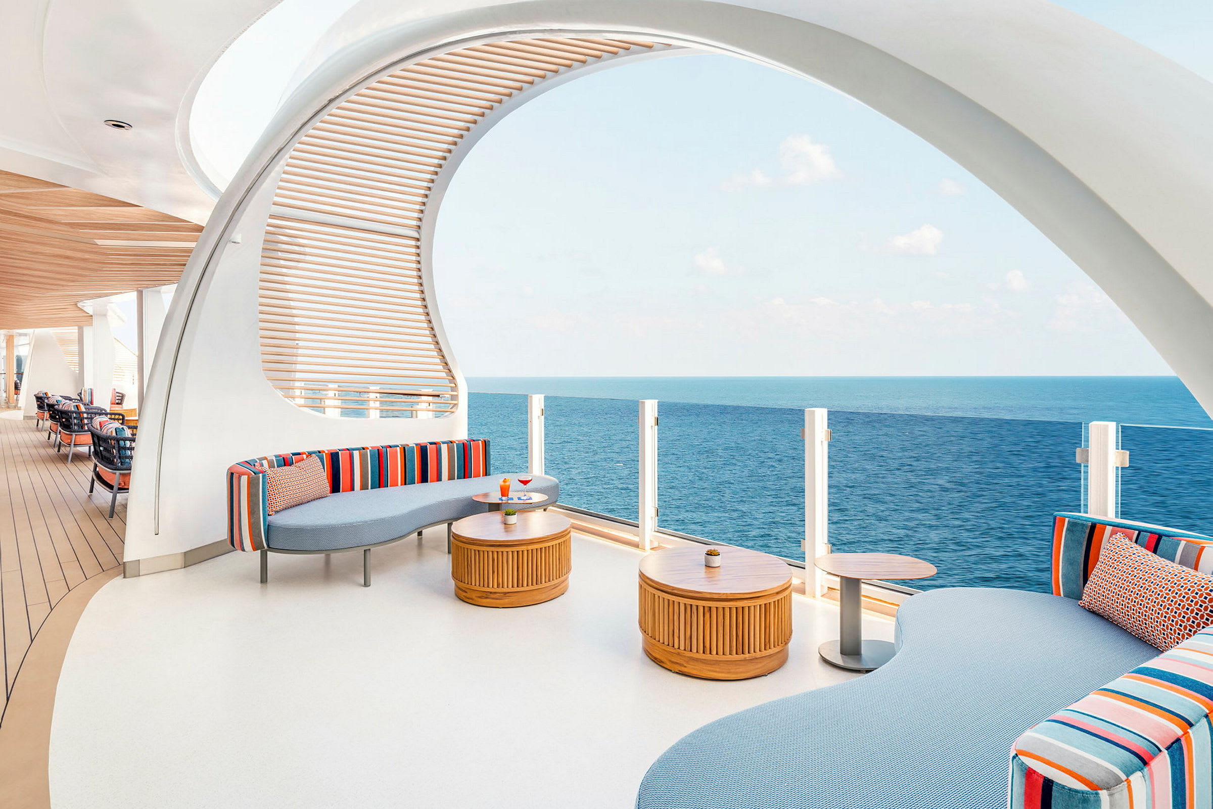 En modern lounge med färgglada soffor, träbord och utsikt över havet. (AI-genererad text)