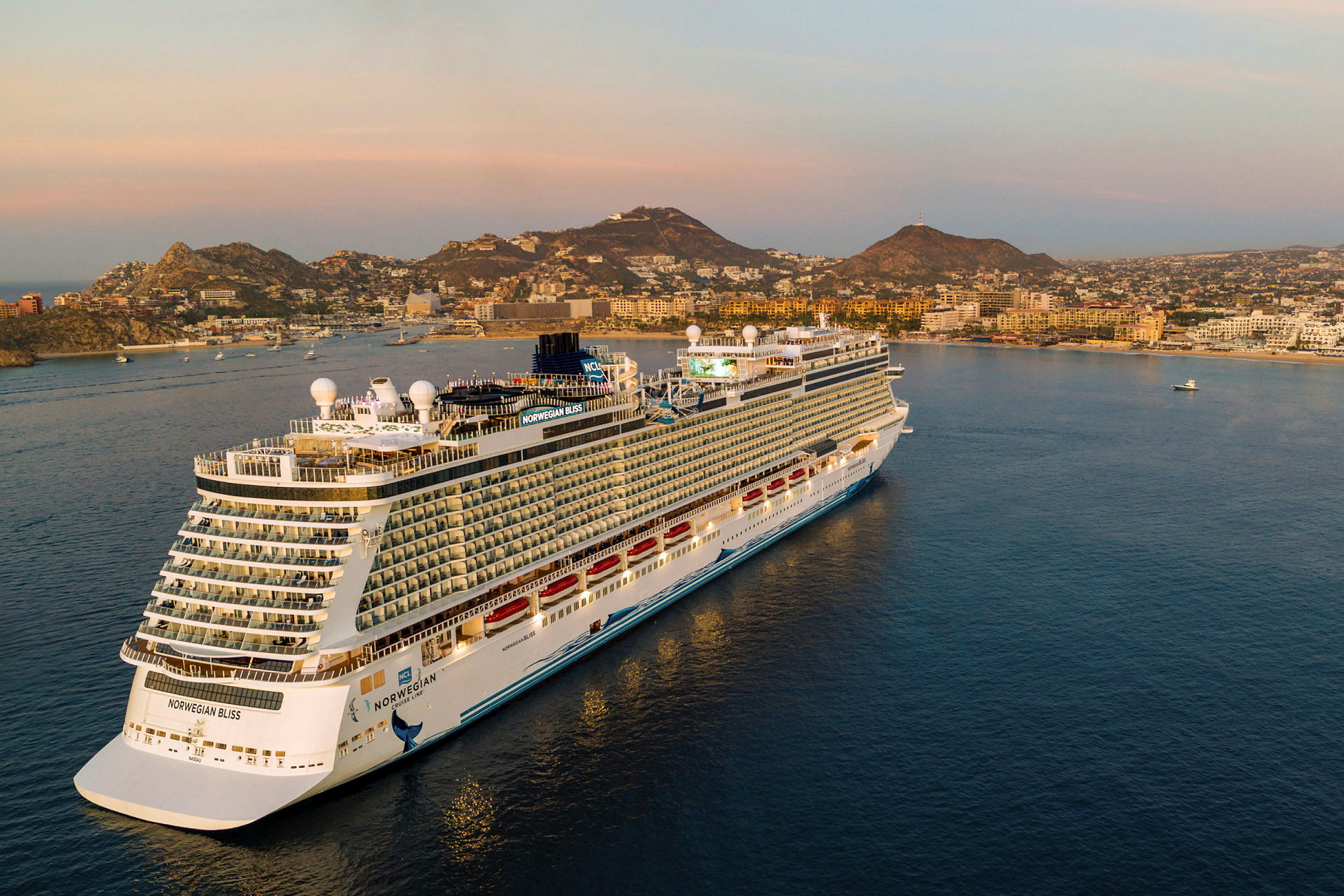 En bild av kryssningsfartyget Norwegian Bliss vid en kuststad under solnedgången. (AI-genererad text)