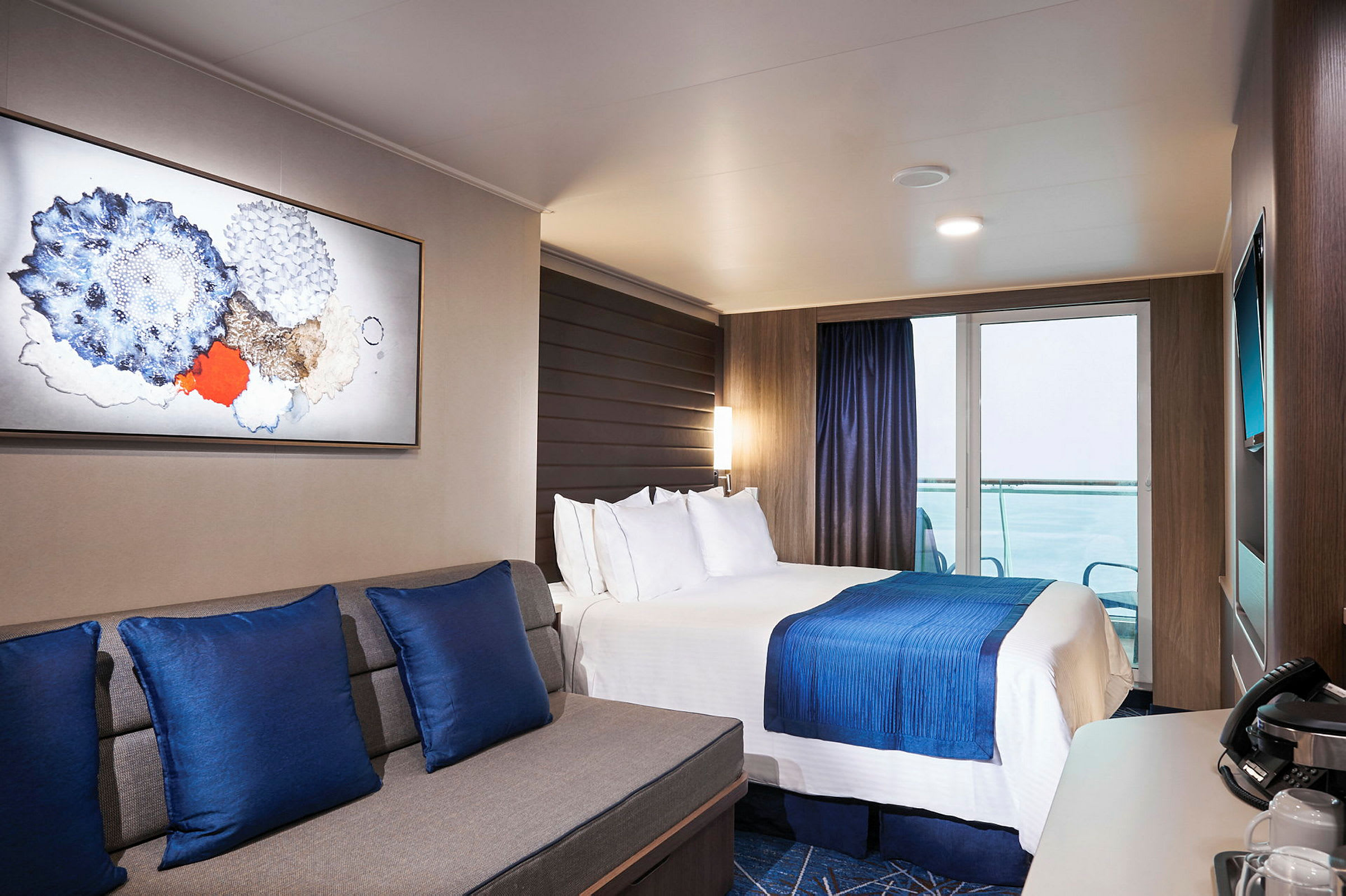 Ett modernt hotellrum med en dubbelsäng, blå dekorativa inslag och en sittgrupp. (AI-genererad text)