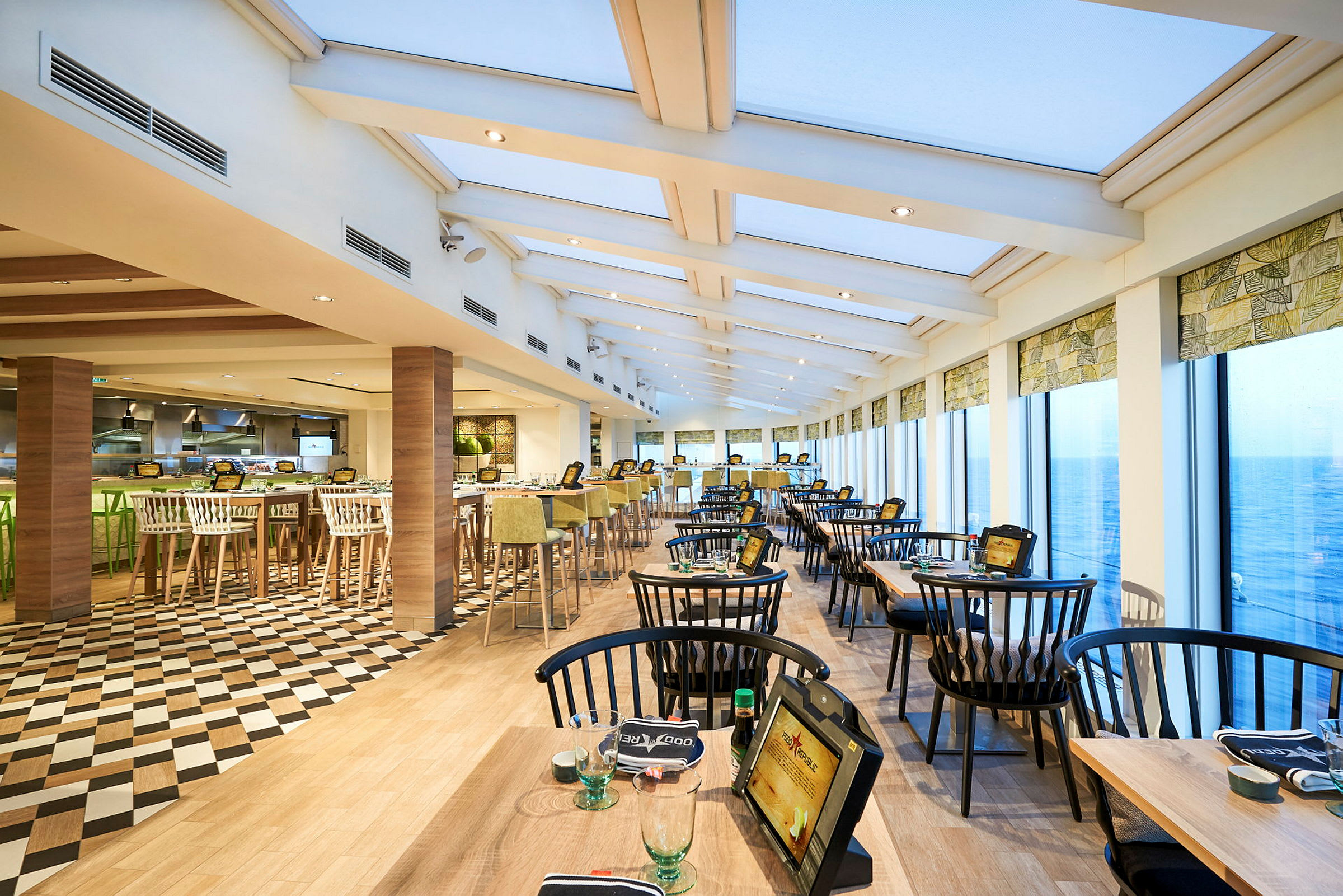 Utsikt av en restaurang med stora fönster och sittplatser ordnade vid bord. (AI-genererad text)