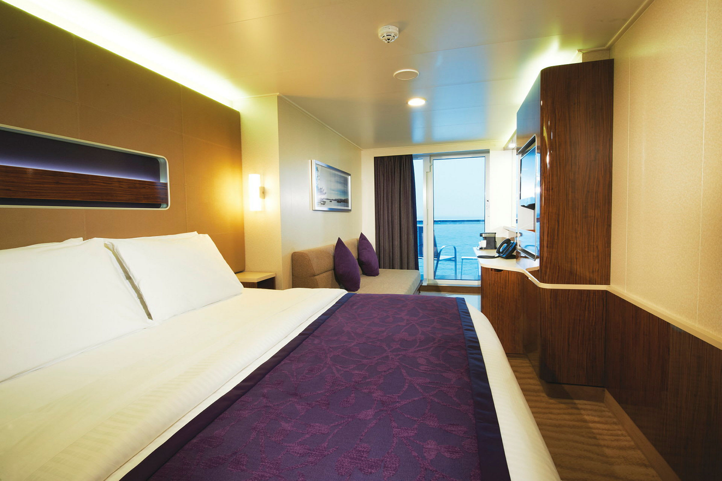 Hotellrum med dubbelsäng, mörklila sängkläder och havsutsikt. (AI-genererad text)