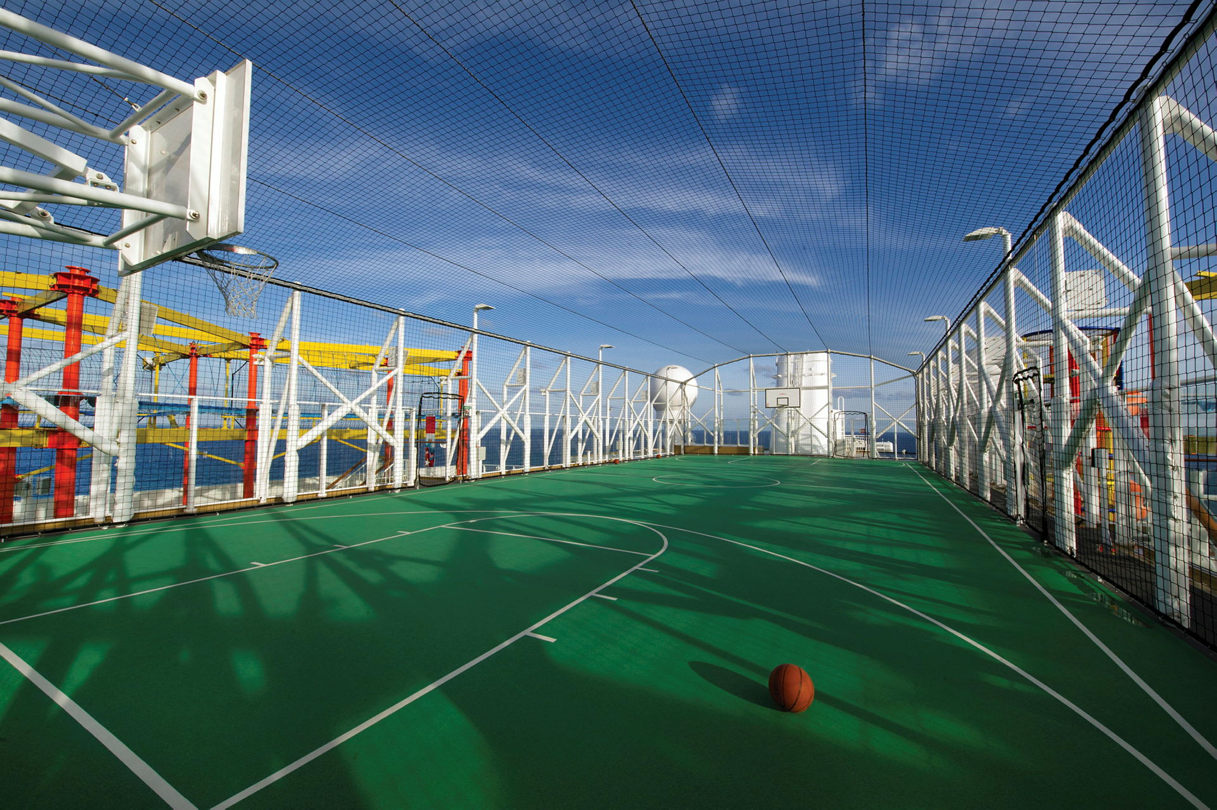 En basketplan med nät runt och en basketboll på planen. (AI-genererad text)