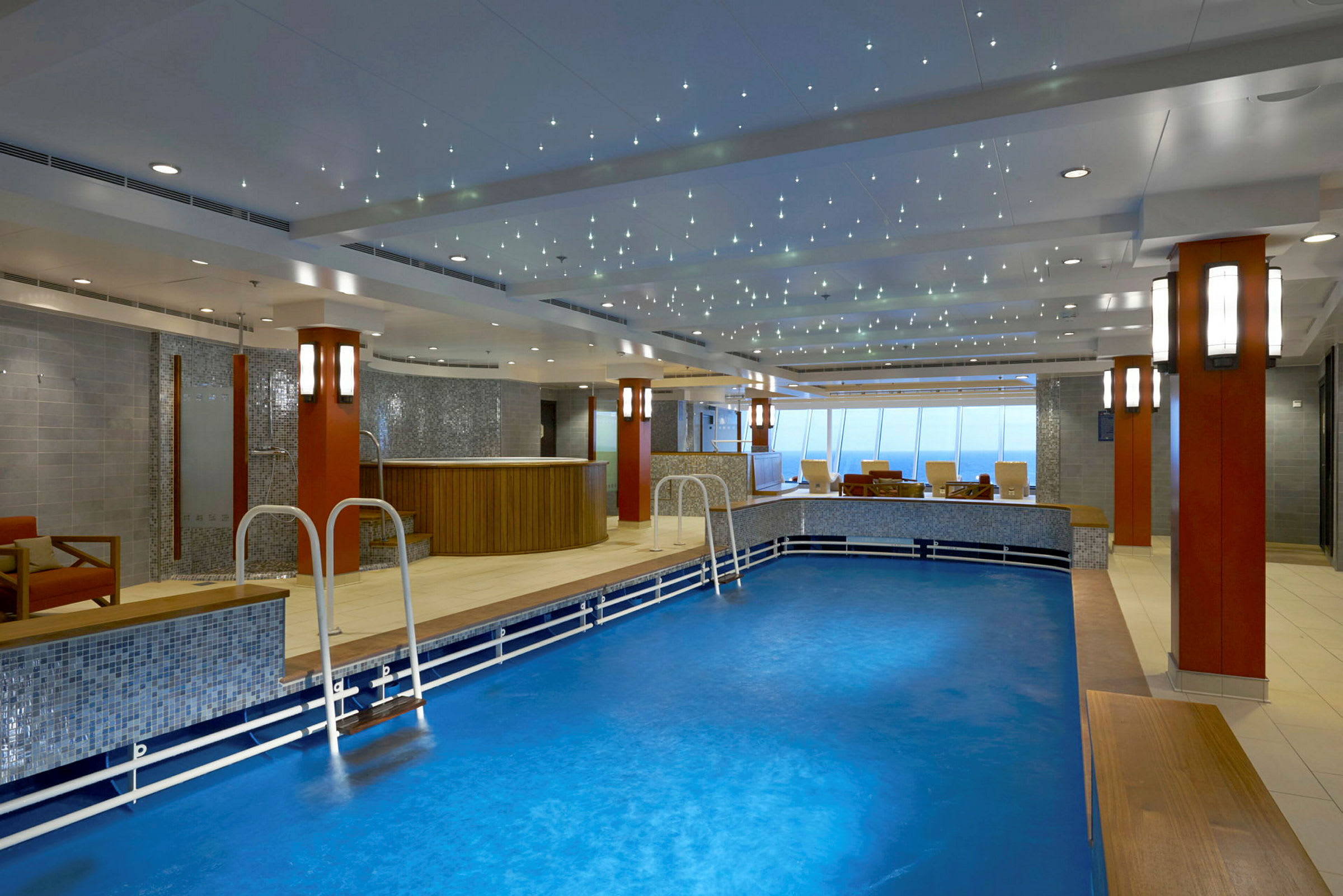 Inomhuspool med sittplatser och dekorerad belysning i taket. (AI-genererad text)