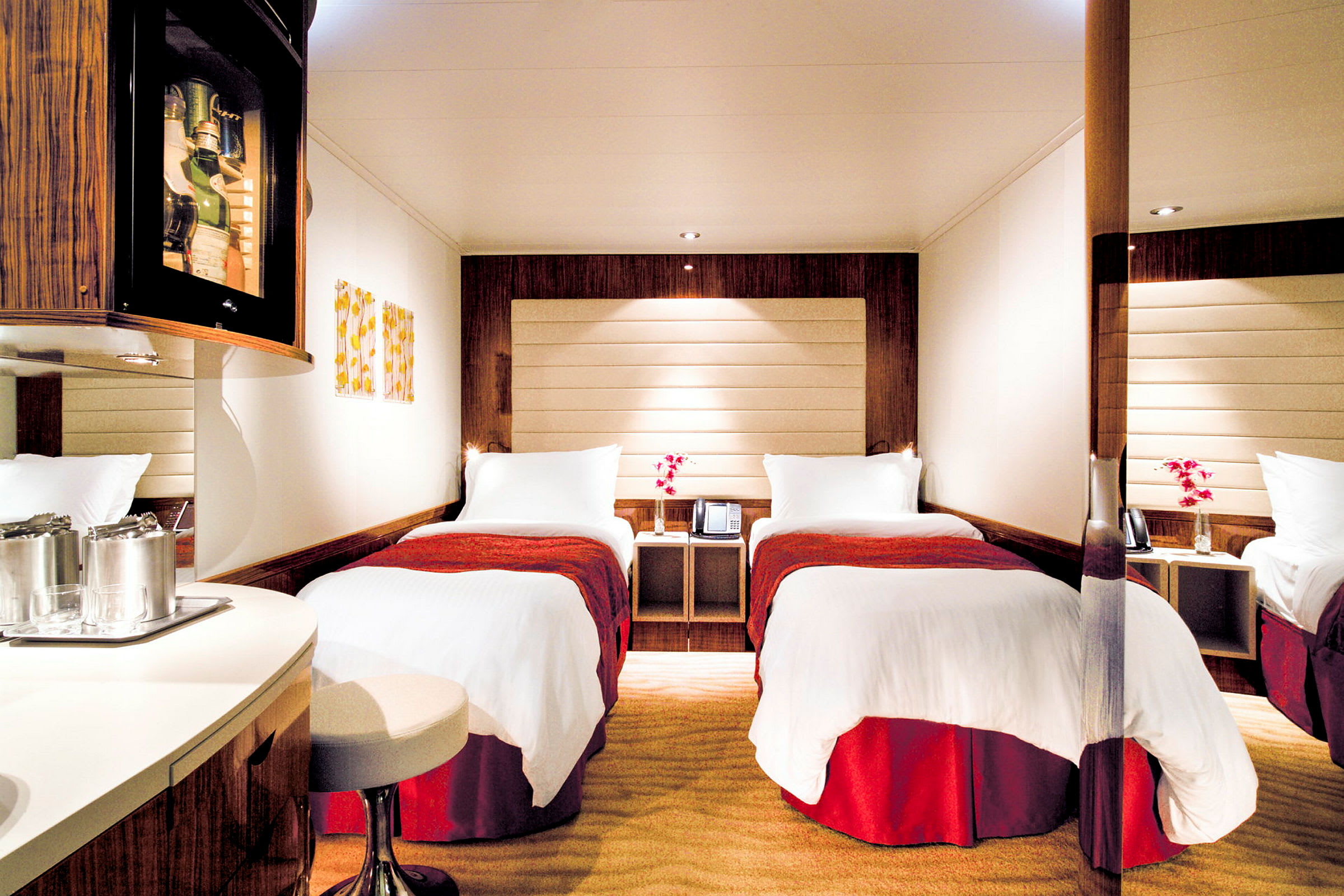 Två enkelsängar med vita sängkläder och röda överkast i ett hotellrum med modern inredning. (AI-genererad text)