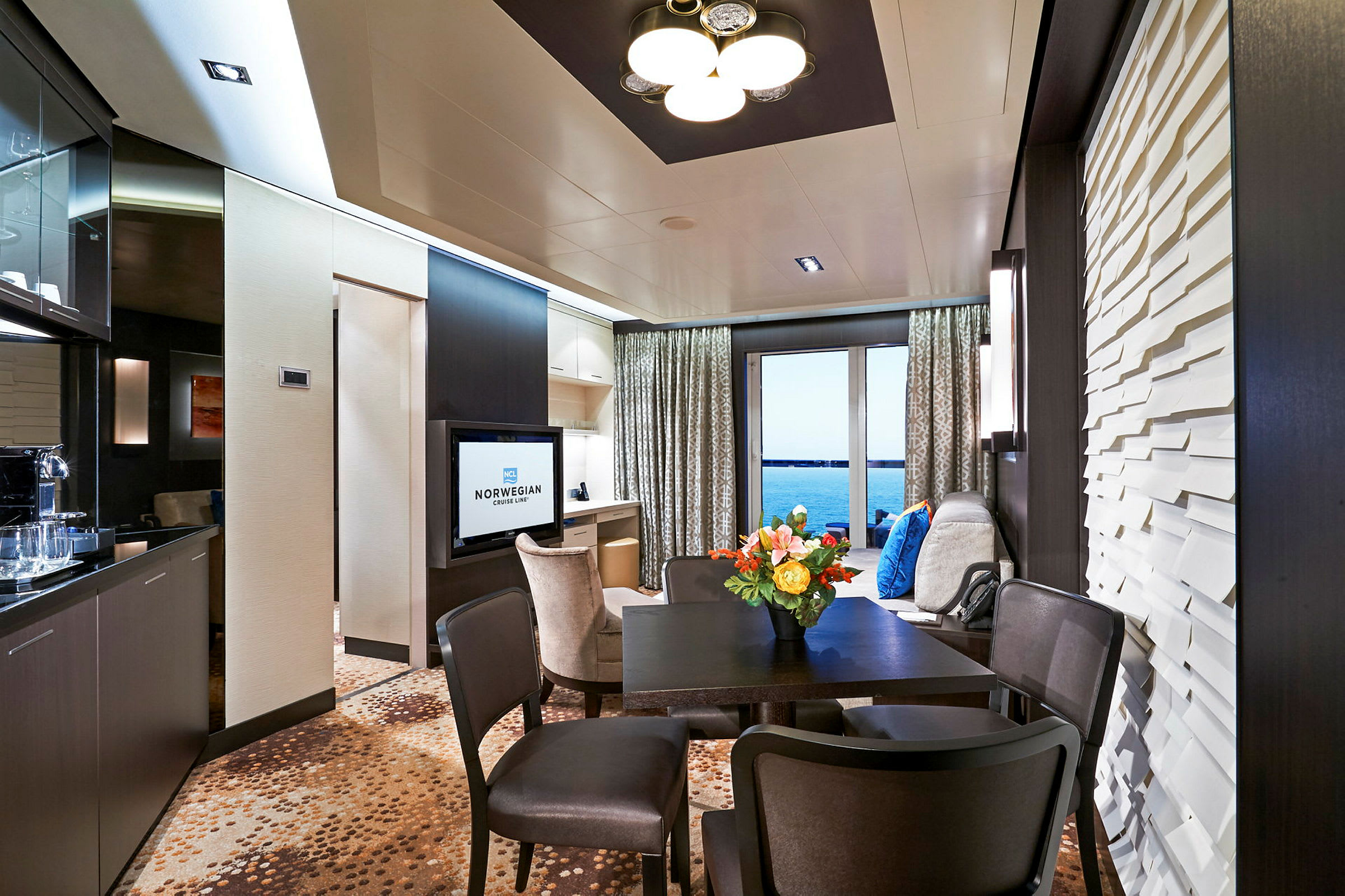 Interiör av en modern hotellsvit med ett bord, stolar och en utsikt över havet. (AI-genererad text)
