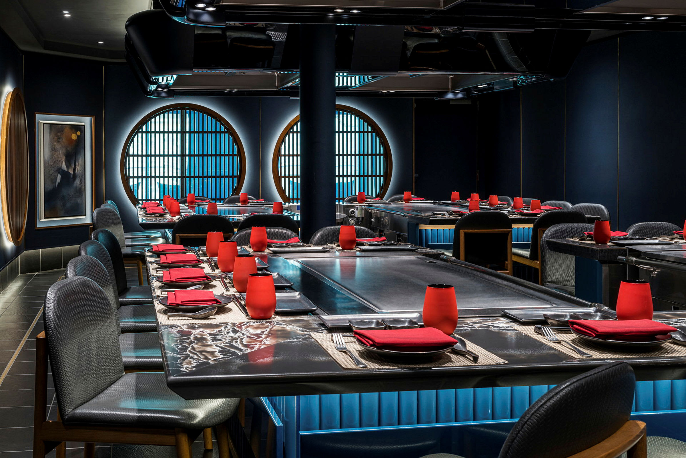 Bild på en stilfull restaurang med mörk inredning, röda detaljer och stora cirkulära fönster. (AI-genererad text)