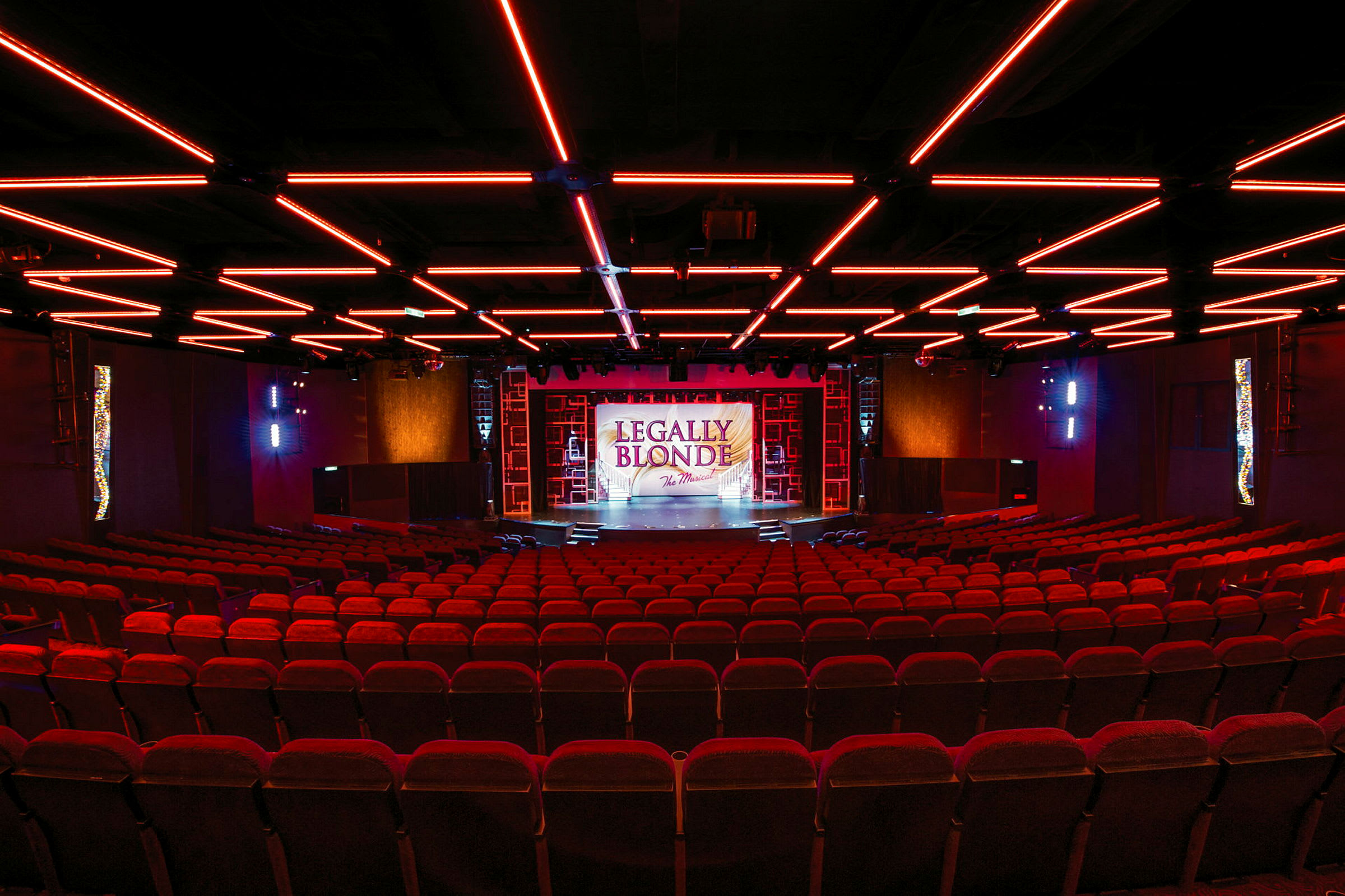 En teater med röda säten och en upplyst scen med texten 'Legally Blonde'. (AI-genererad text)